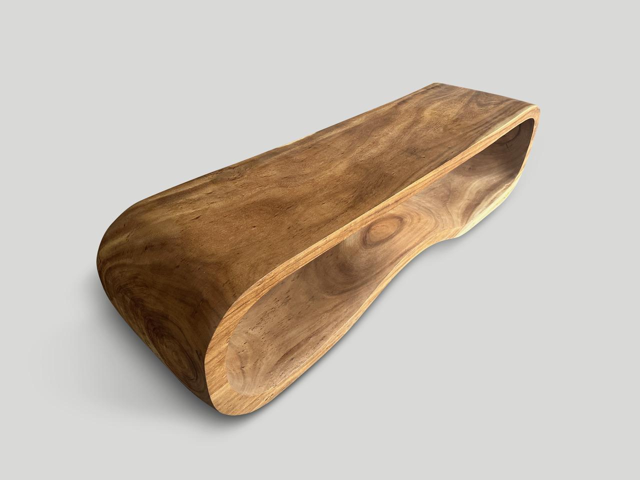 Impressive one of a kind bench or coffee table hand carved seamlessly from a single piece of suar wood. Finished with a natural oil revealing the beautiful wood grain. Both usable and sculptural.

Own an Andrianna Shamaris original.

Andrianna