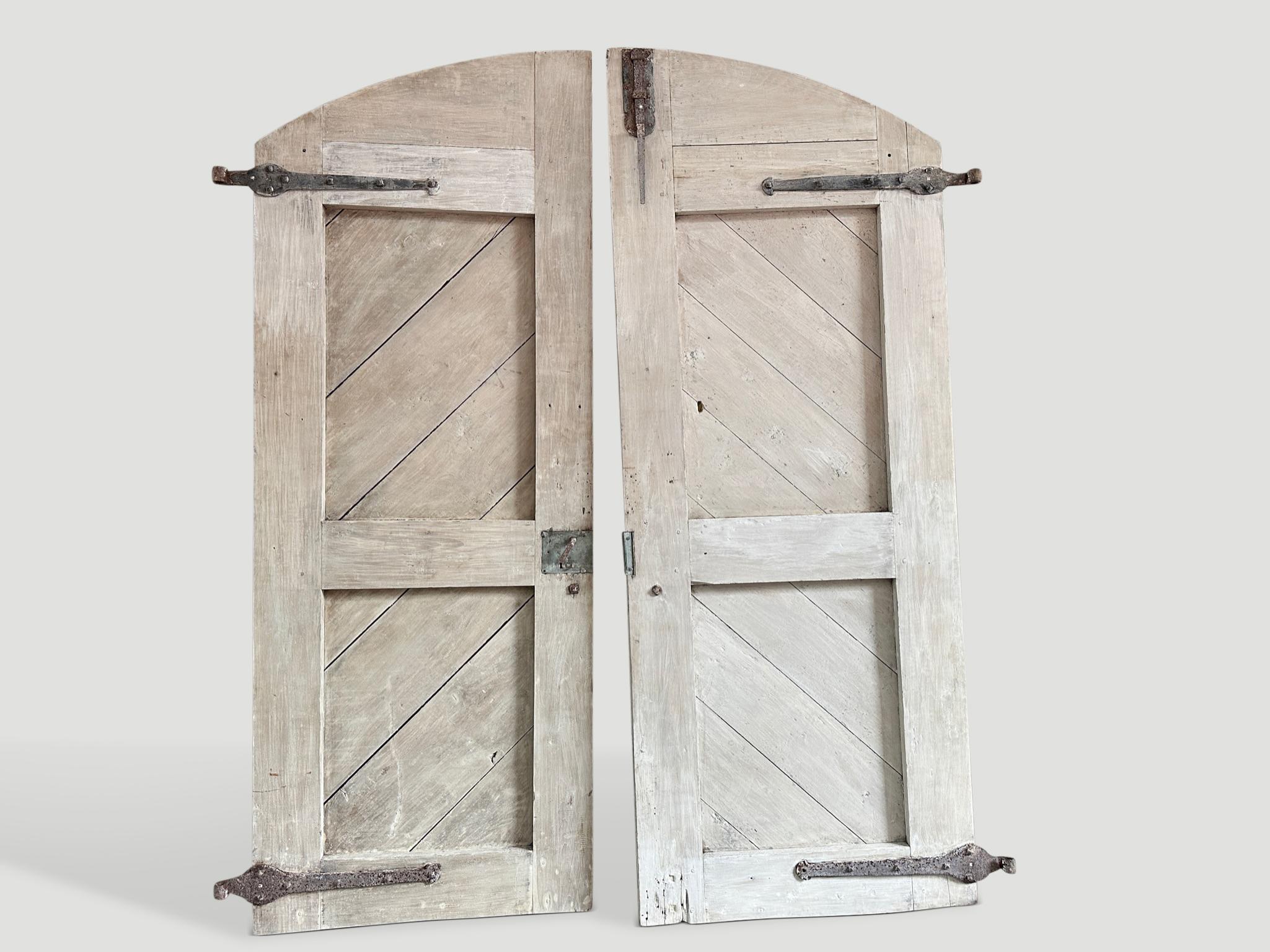 Beautiful teak wooden doors, retaining their original hardware. Installed as doors, hung on the wall as art, as a head board or dining table. A multitude of uses for this set of rare doors. We bleached the wood and then added a light white wash