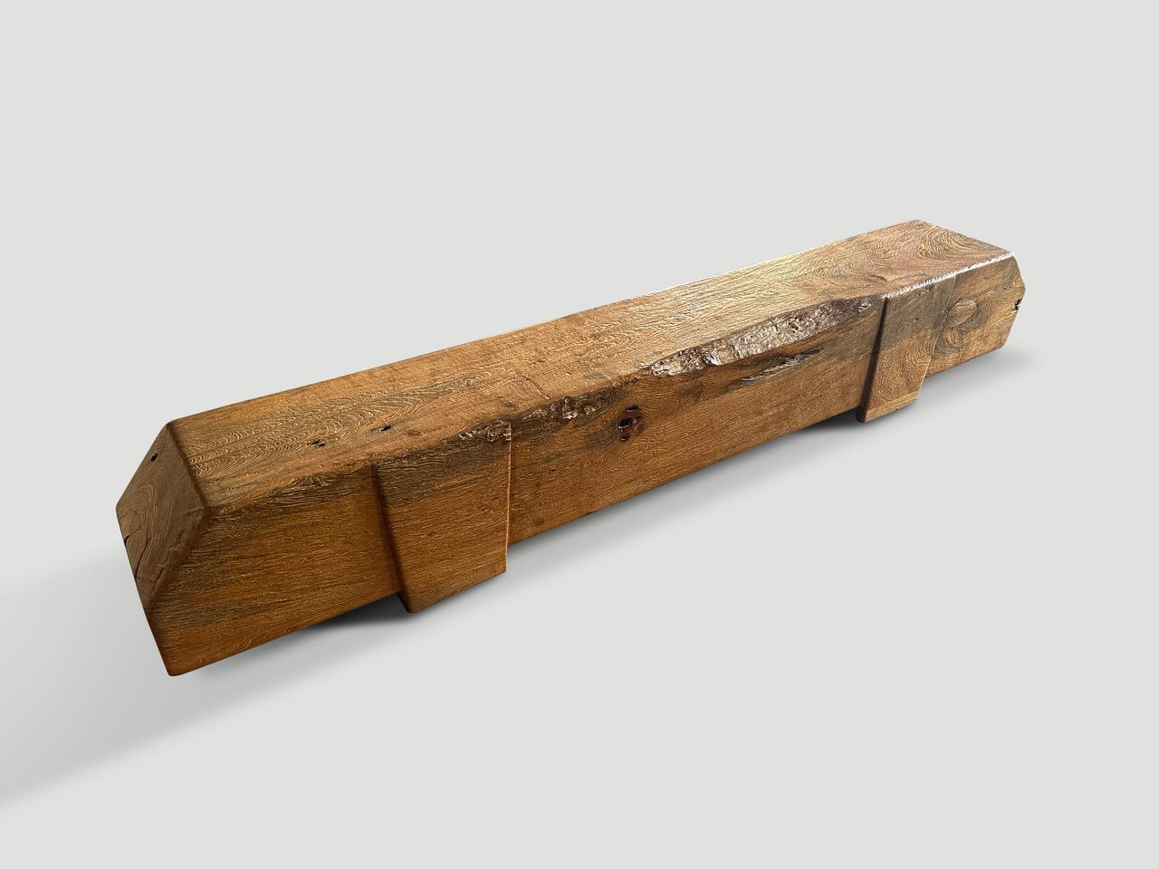 Impressive reclaimed ancient teak log bench. The log is fourteen inches thick and floats two inches off the floor on minimalist hand carved legs inset into the wood. We added a natural oil revealing the beautiful wood grain and unique erosion. It’s