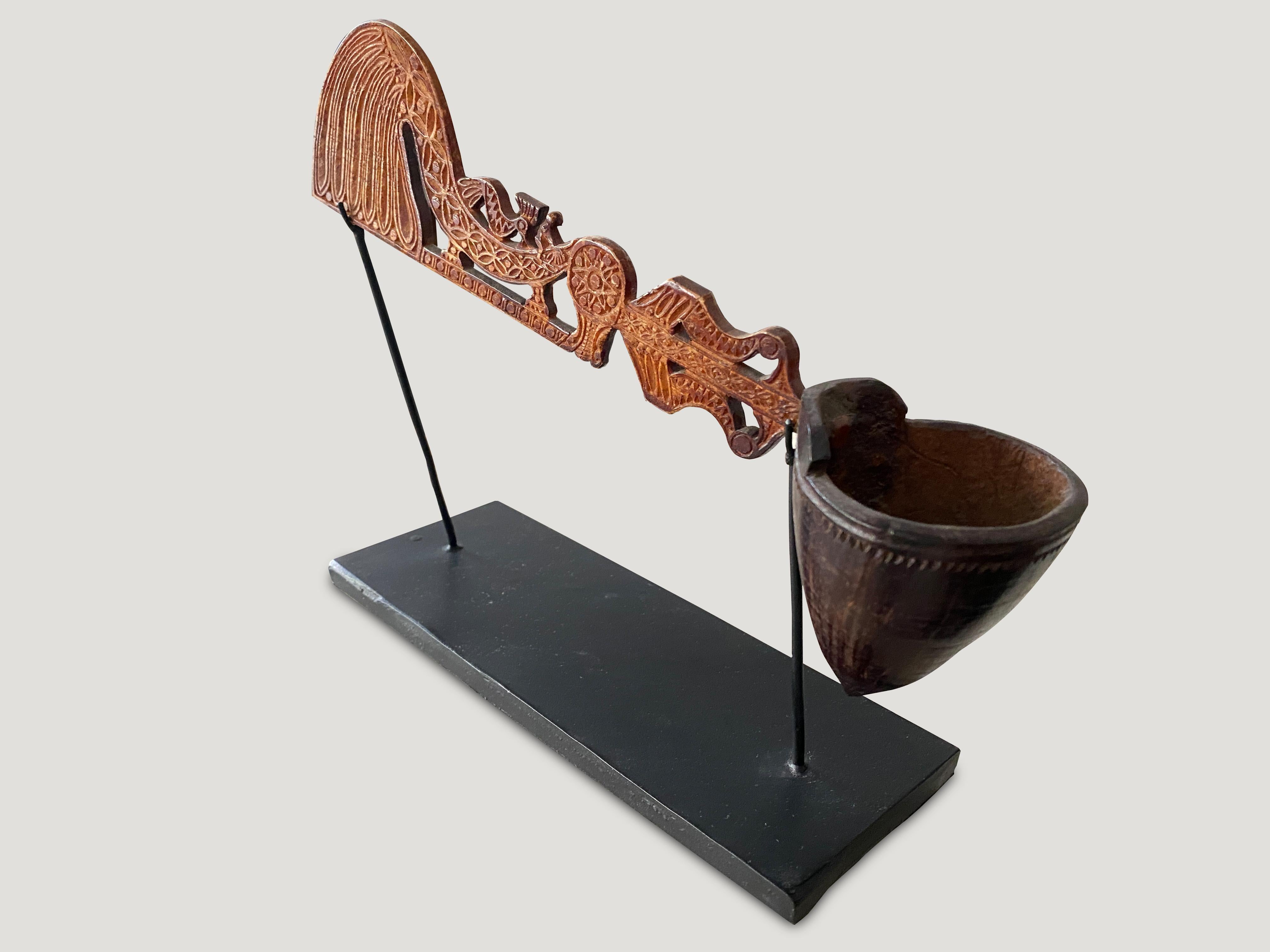 Stunning intricate carving on this hand carved museum quality wooden ladle from Sumatra, circa 1900. Set on a minimalist black metal stand.

This hand carved ladle was sourced in the spirit of wabi-sabi, a Japanese philosophy that beauty can be