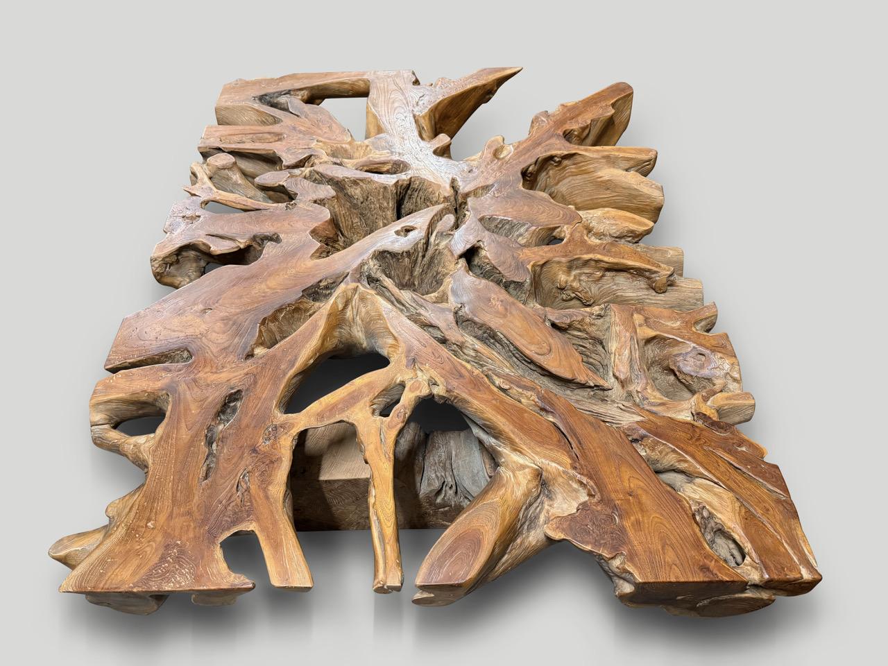 Un'imponente lastra di radice di teak vecchia di un secolo con una bellissima patina che racconta la sua ricca storia. Abbiamo aggiunto delle gambe in blocco di teak e le abbiamo rifinite con un olio naturale che rivela le squisite venature del