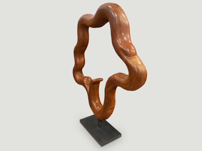 Minimalist organic circle sculpture hand carved from a single piece of reclaimed mahogany wood with beautiful patina. Set on a modern black metal stand. Dimensions: 41