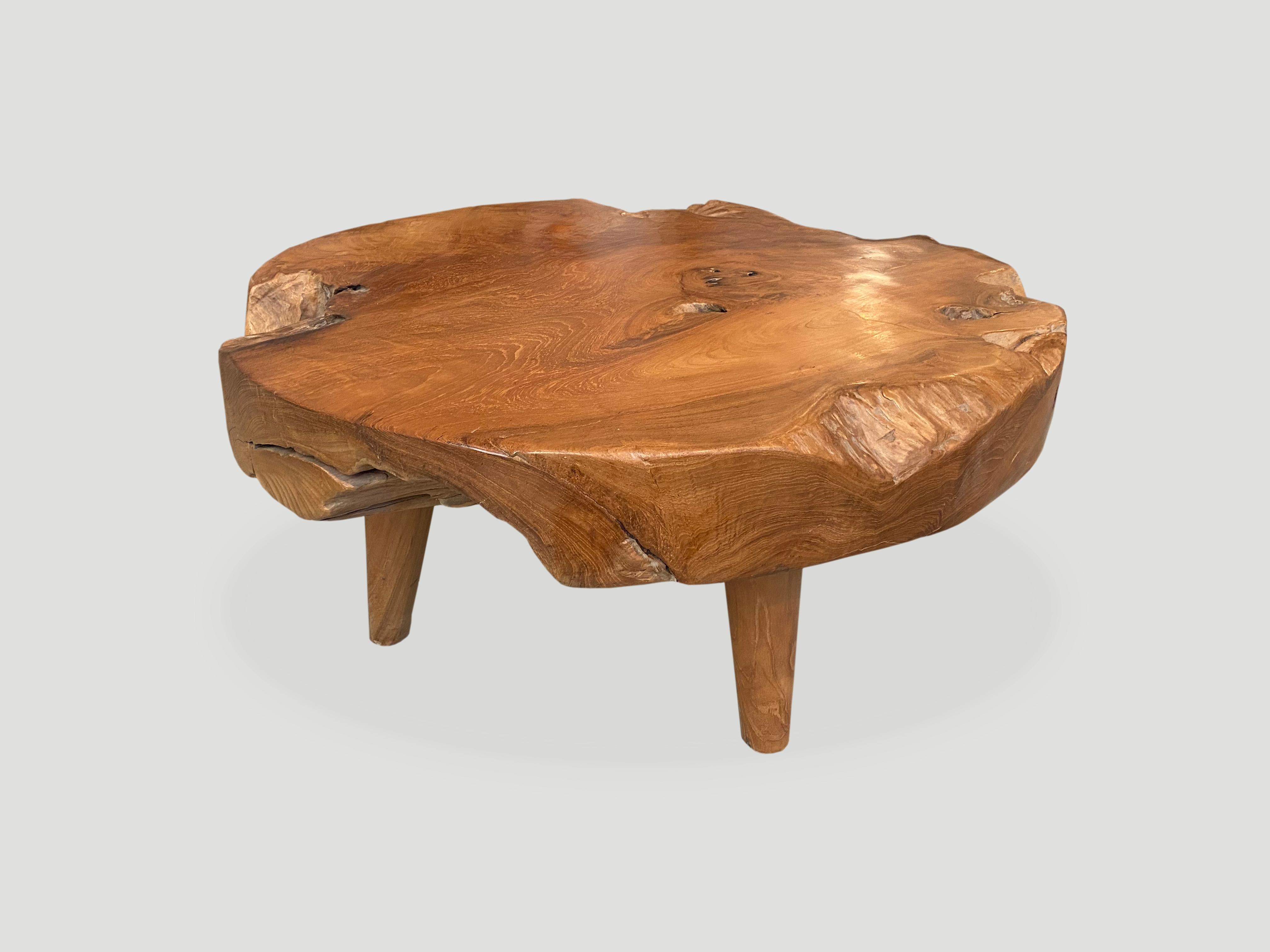 Impressive five inch thick natural teak wood coffee table carved from a single log. Floating on midcentury style cone shaped legs. Organic with a twist. We have a collection. The size and price reflect the one shown.

Own an Andrianna Shamaris