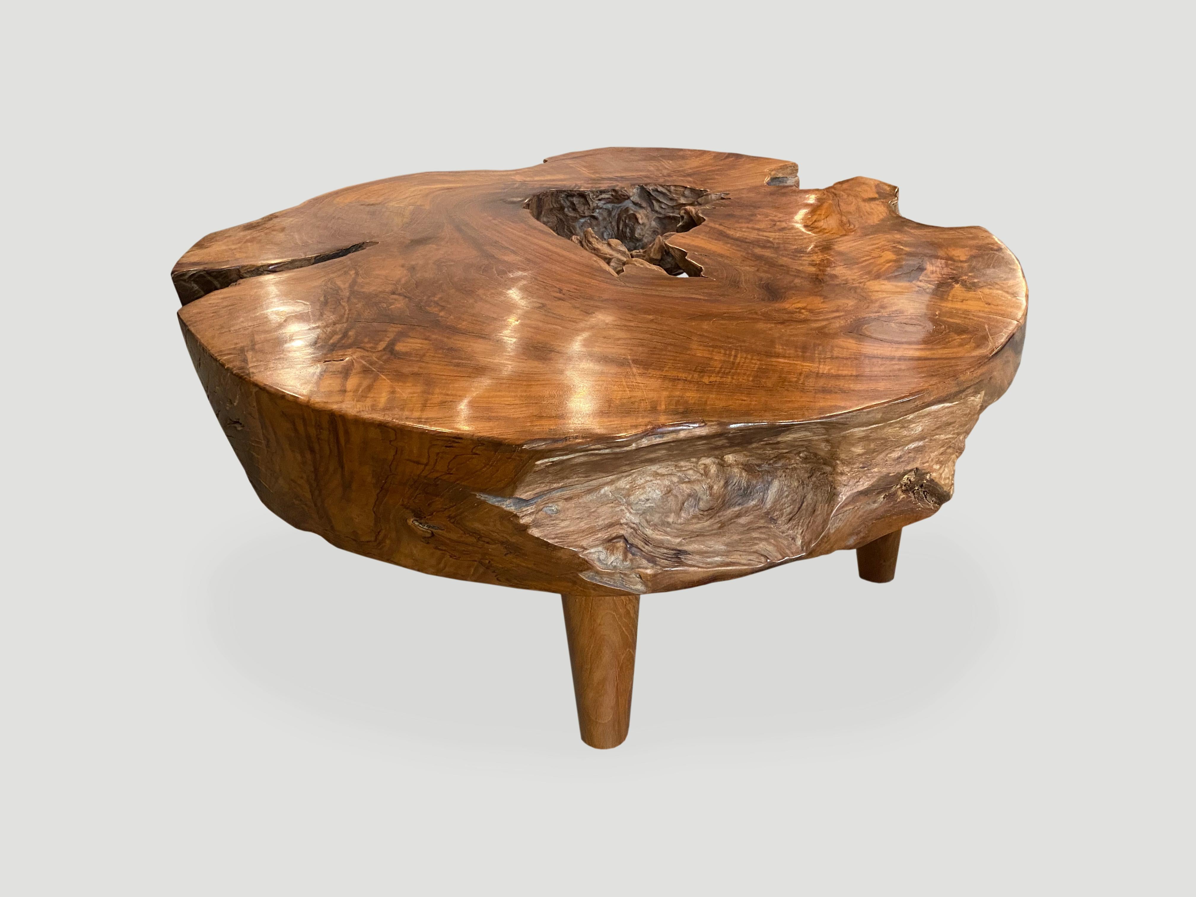 Impressive six inch thick natural teak wood coffee table carved from a single log. Floating on midcentury style cone shaped legs. Organic with a twist. We have a collection. The size and price reflect the one shown.

Own an Andrianna Shamaris