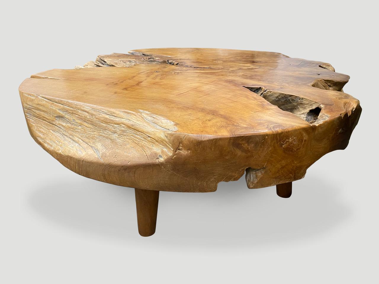 Impressive five inch thick teak wood coffee table hand carved from a single log. Floating on mid-century style cone legs. Organic with a twist. Finished with a natural oil revealing the beautiful wood grain.

Own an Andrianna Shamaris