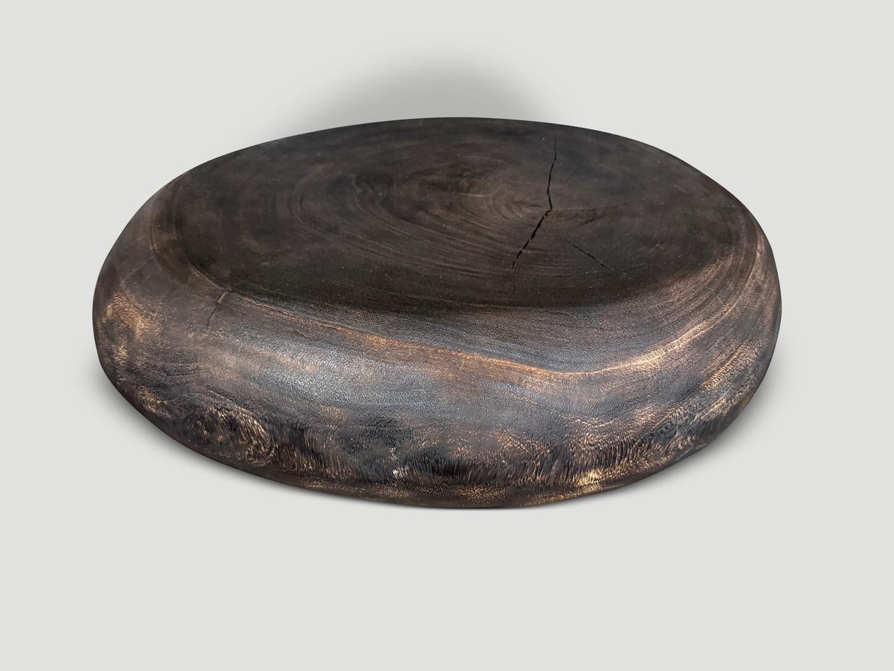 Una mesa de centro minimalista de perfil bajo y estilo guijarro. Tallado a mano en una sola pieza de madera de suar. Carbonizado de un marrón intenso que revela la veta única de la madera. Todo está en los detalles. Dimensiones completas; Parte
