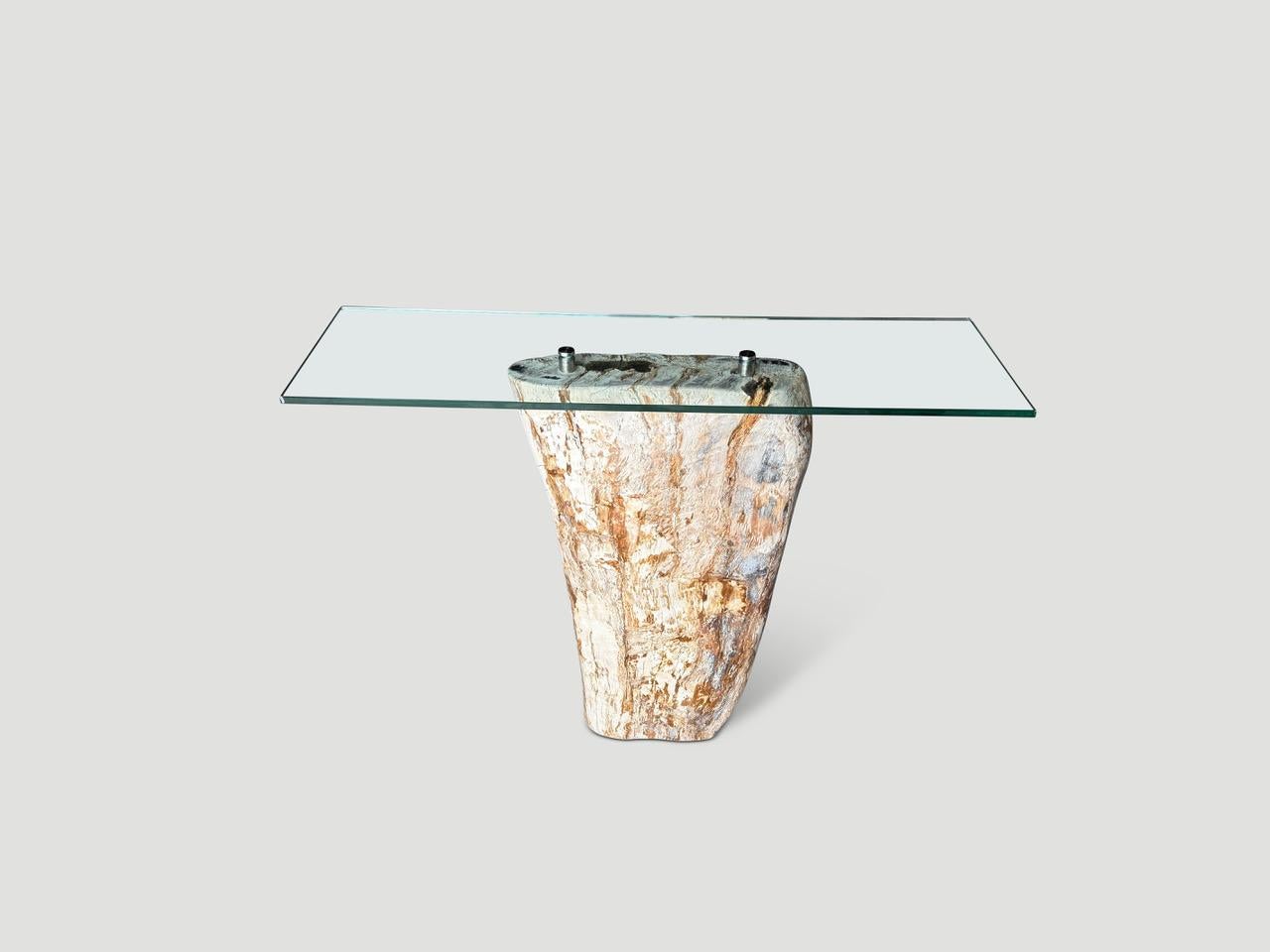 High quality petrified wood console table base with a glass top screwed into the center securely with stainless steel hardware.  It’s fascinating how Mother Nature produces these stunning 40 million year old petrified teak logs with such contrasting