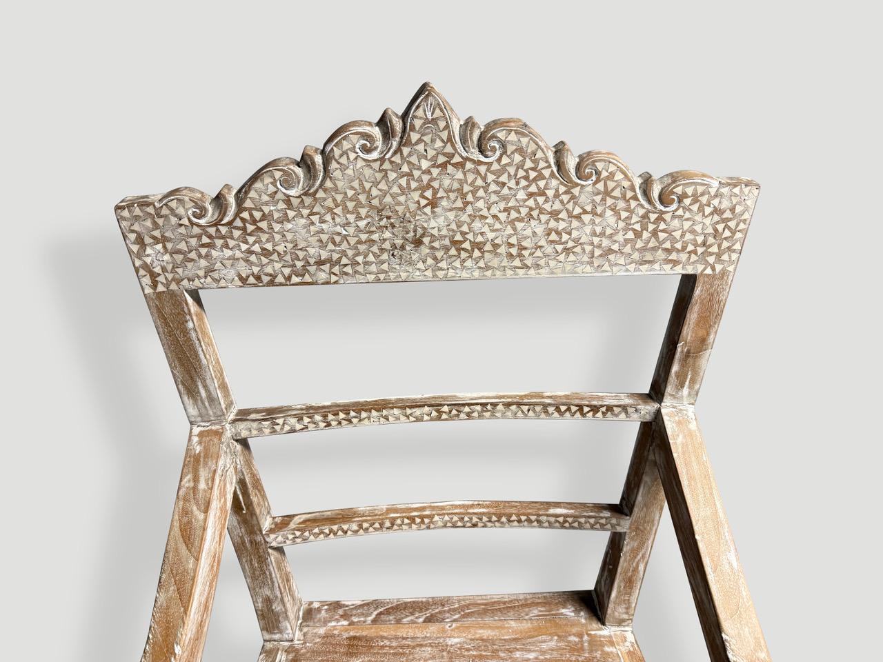 Questa bellissima sedia d'influenza Raffles è intagliata a mano in legno di teak recuperato. Abbiamo trovato una sedia antica e l'abbiamo riprodotta aggiungendo un leggero lavaggio bianco e un intarsio di conchiglie. Tutto sta nei dettagli.