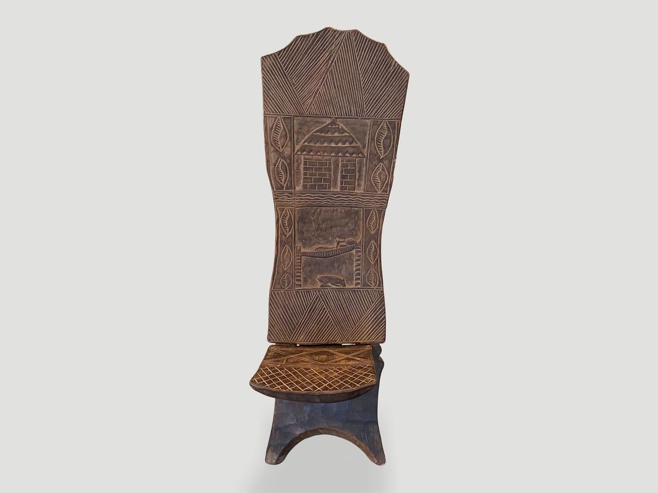 Rare chaise africaine antique sculptée à la main. Belle patine sur l'unique dossier en bois, aux multiples motifs. Cette chaise pliante est fabriquée à partir d'une seule pièce de bois ébéniste d'Afrique de l'Ouest. Également appelée chaise de