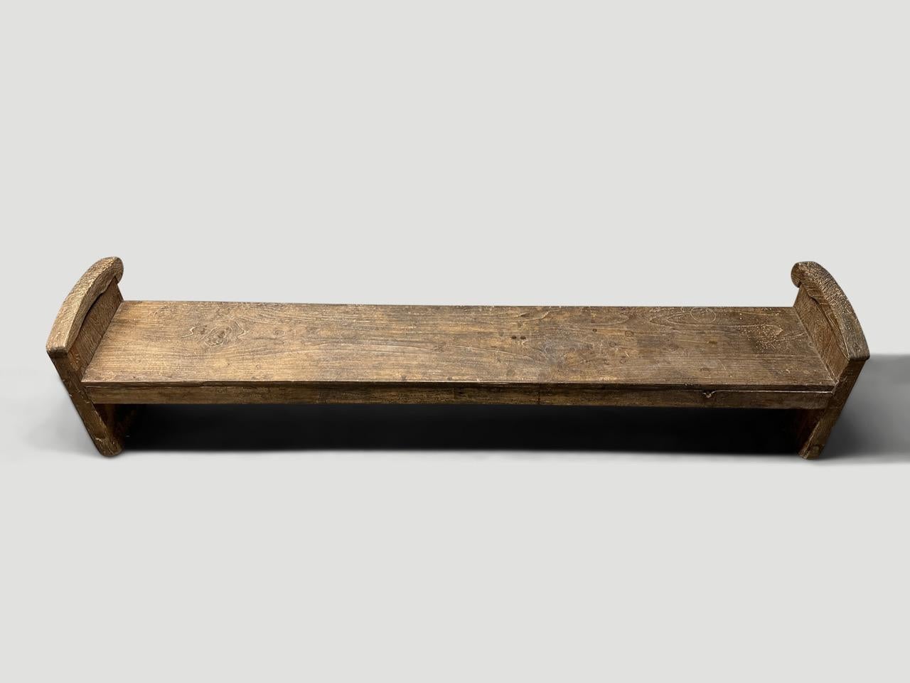 Beautiful patina on this rare antique bench from Madura. Circa 1940. The seat section slopes. Full dimensions; 77” wide x 14” deep x 10.5” seat at the front  x 12.5” seat at the back x 17” arm at highest point.

This bench was hand made in the