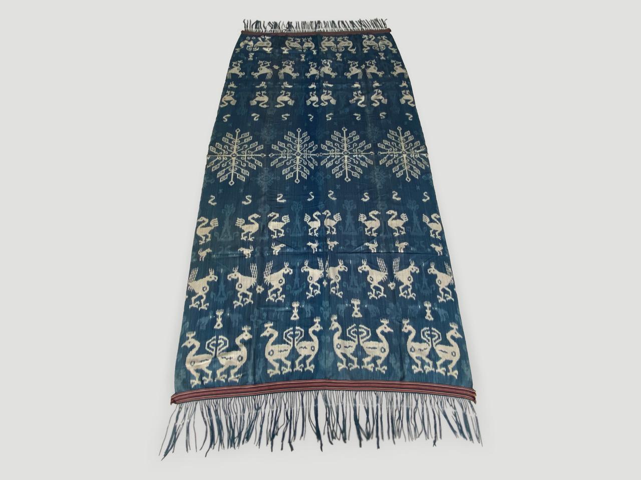 Beautiful soft Ikat, with stunning seven inch tassels, on this rare bold indigo and white textile from Sumba. Fabulous on a sofa, bed, a wall hanging, or even to wear as a shawl. Mythical characters, lizards, horses and birds intermingle in this
