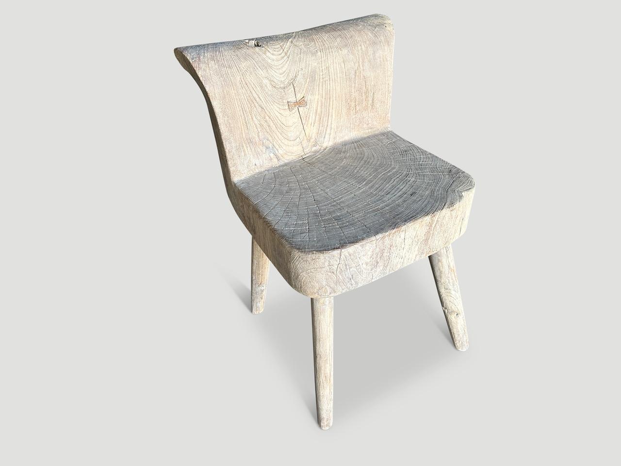 Beautiful chair hand carved from a single reclaimed teak wood block. Both usable and sculptural. This can also be used as a side table. The seat and back are one piece of wood with added four minimalist cylinder legs. The stunning patina and grain