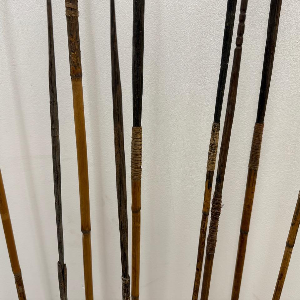 Ein Satz von zehn handgeschnitzten antiken Bambusspeeren steht auf minimalistischen schwarzen Metallsockeln. In Rattan und geschnittenen Bambus eingewickelt. Vollständige Abmessungen: Der höchste Speer ist 60