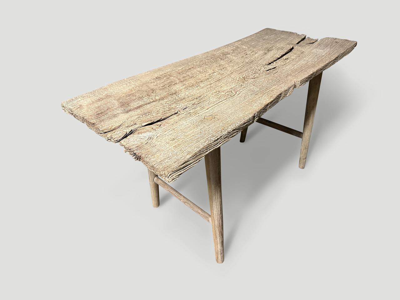 A single antique wood panel with lovely character. We added smooth teak minimalist legs to form this beautiful console or desk. Butterflies are inlaid into the table top. First bleached and finished with a light white wash revealing the unique wood