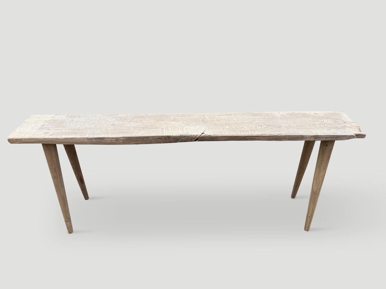 A single antique wood panel with lovely character. We added smooth teak minimalist legs and a butterfly inlaid into the top to form this beautiful console. First bleached and finished with a secret ingredient revealing the stunning wood grain. It’s