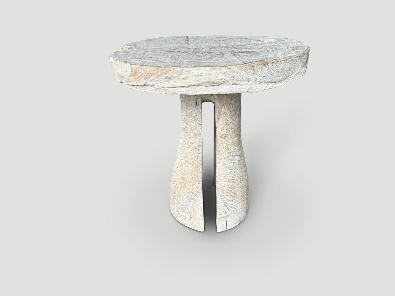 Magnifique table d'appoint dotée d'un épais plateau en bois de teck ancien organique et d'une base minimaliste aux découpes élégantes. Nous avons ajouté un léger lavis blanc et des papillons incrustés sur le dessus et la base. Tout est dans les