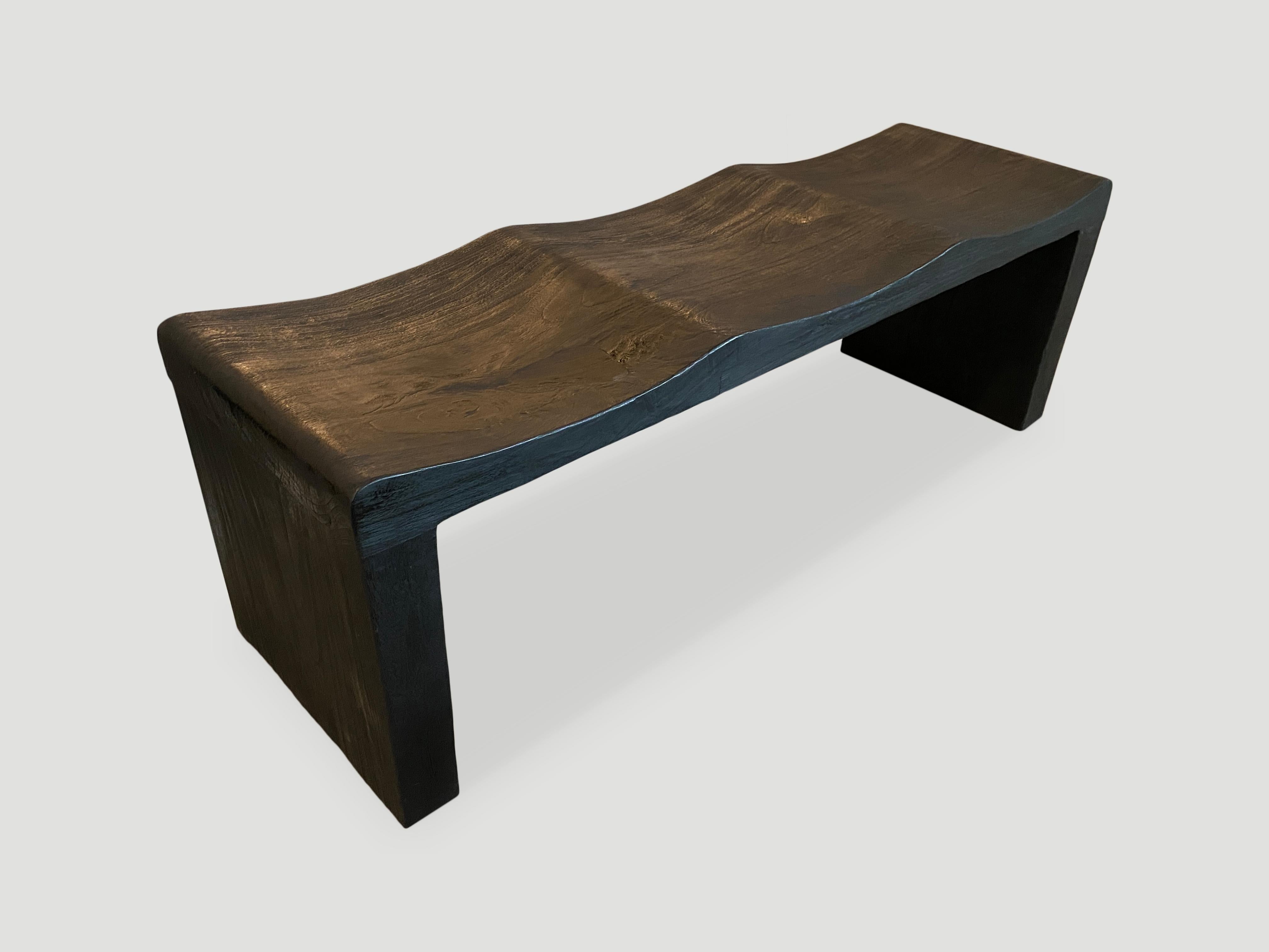 The wave bench represents a sleek, modern aesthetic, designed to provide comfort and durability. Solid reclaimed teak wood is hand carved from a single thick slab into a wave design. Burnt, sanded and sealed revealing the beautiful wood grain.