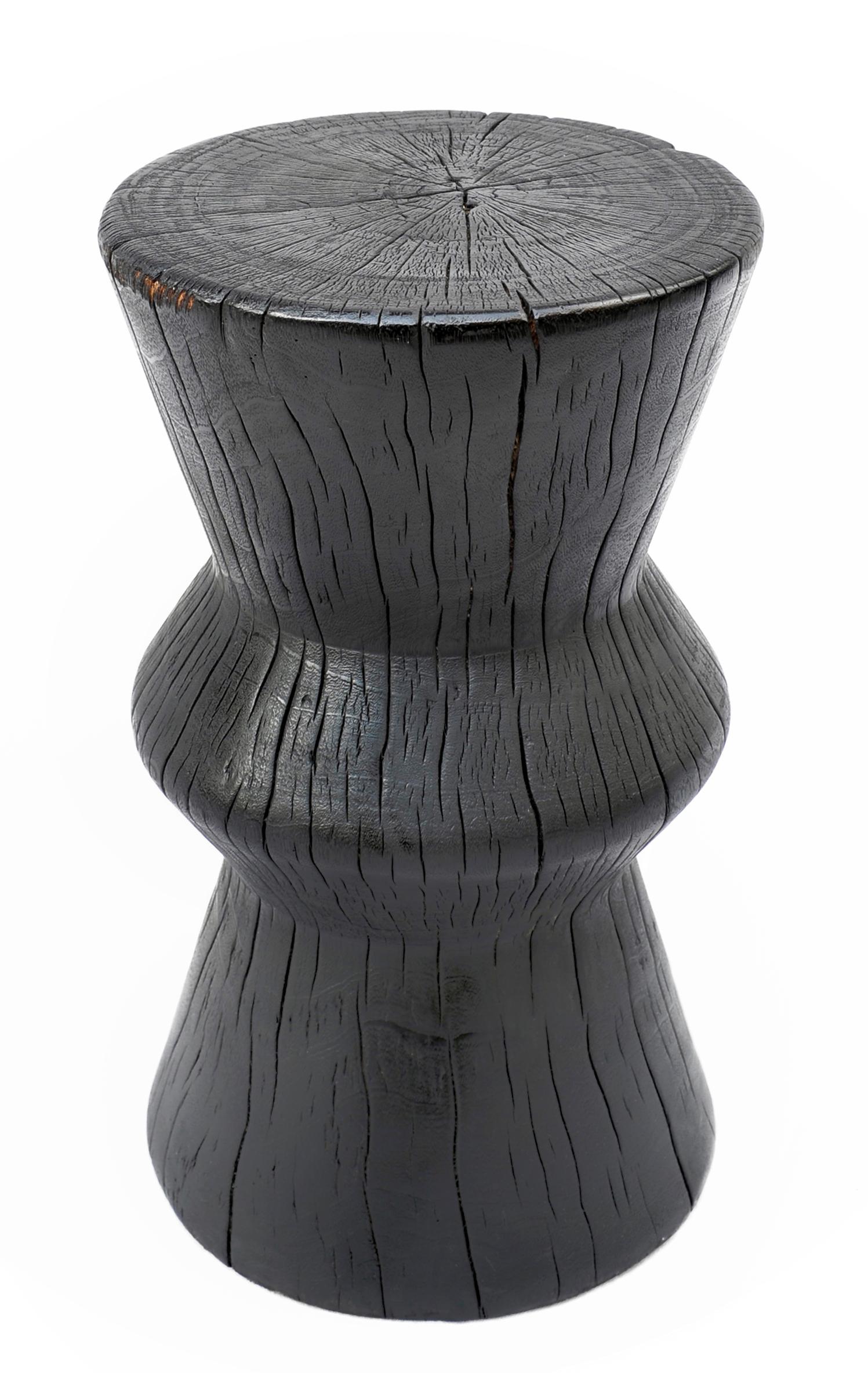 Solid hourglass shaped tamarind wood side table. Burnt, sanded and sealed.

The Triple Burnt collection represents a unique line of modern furniture made from solid organic wood. Burnt three times to produce a rich, charcoal finish with impressive