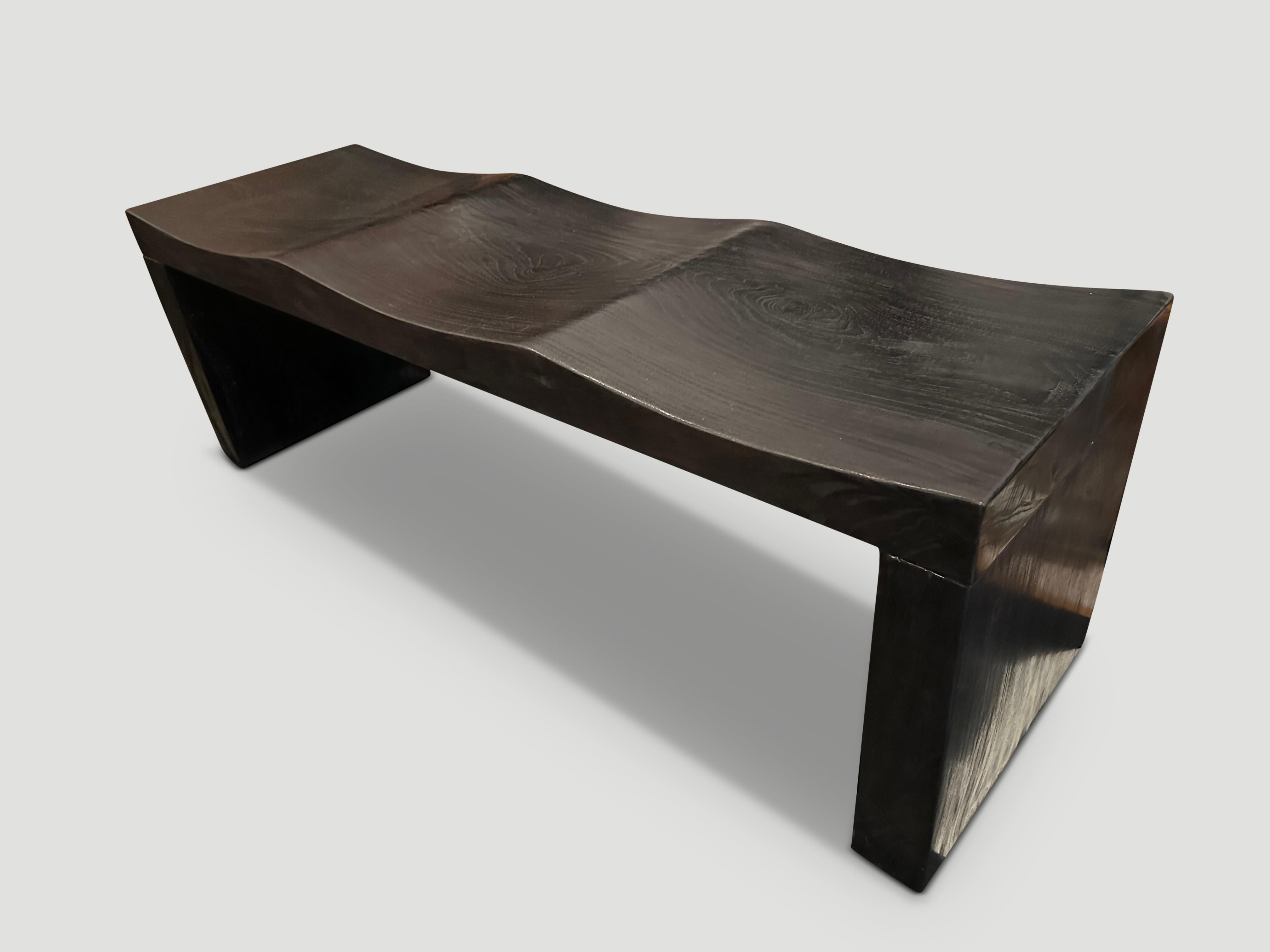 The wave bench represents a sleek, modern aesthetic, designed to provide comfort and durability. Solid reclaimed teak wood is hand carved from a single thick slab into a wave design. Burnt, sanded and sealed revealing the beautiful wood grain.