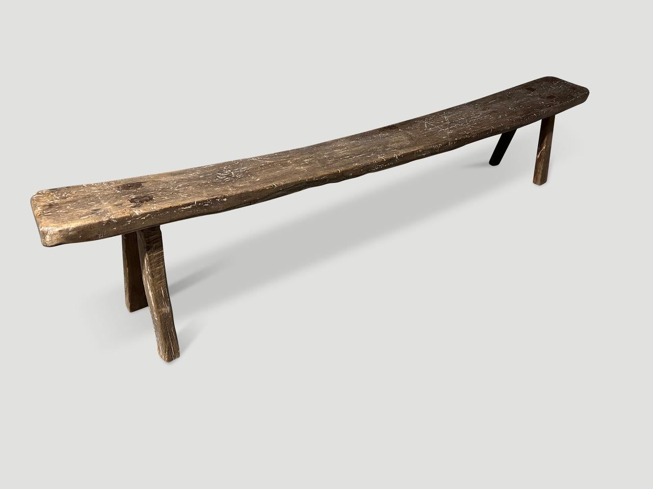 Antique Wabi Sabi teak bench celebrating the cracks and crevices and all the other marks that time and loving use have left behind. Beautiful patina on this ancient thick single top. Full dimensions; The center is 15.5” high and graduates to 18”