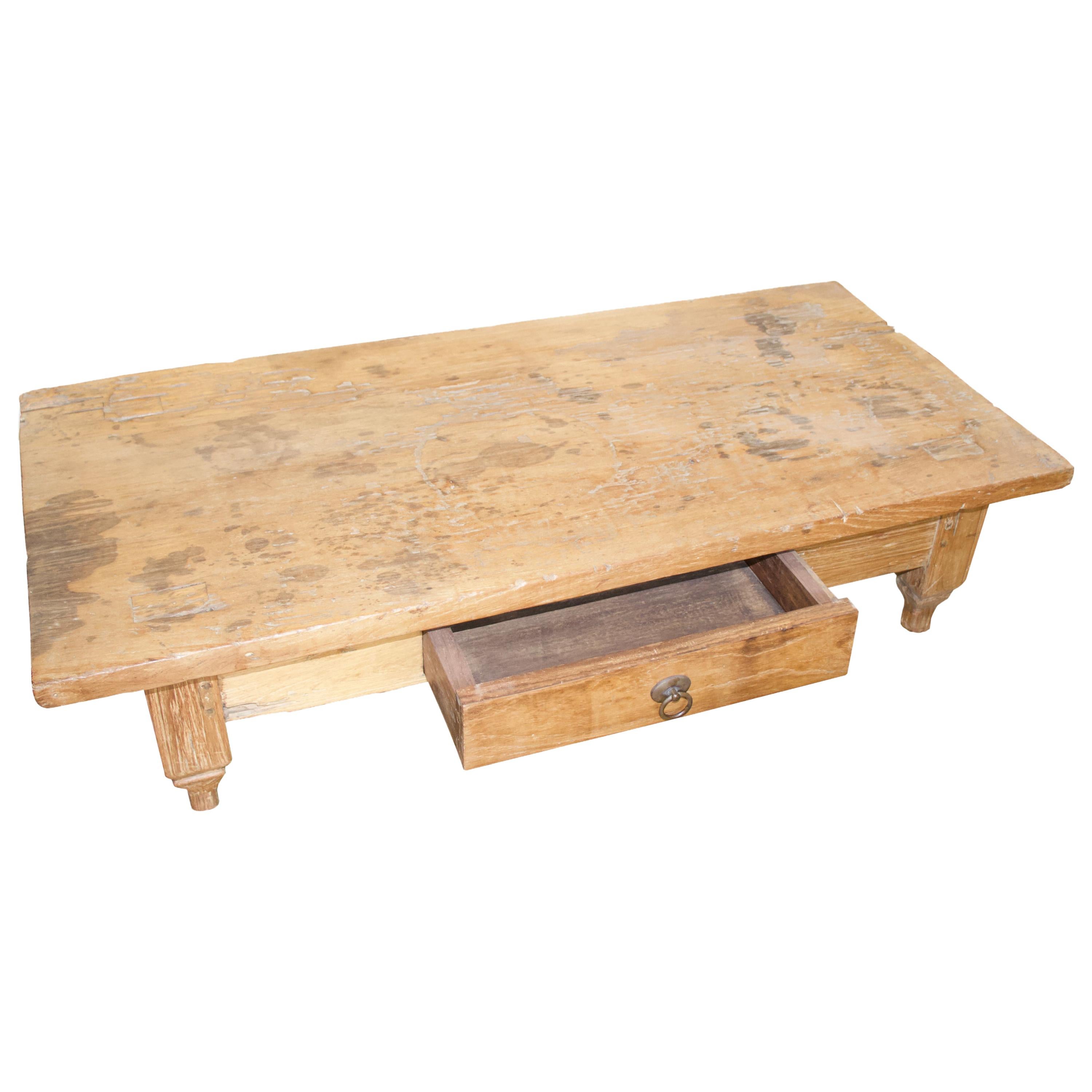 Antique coffee table with a single drawer and the top made from a single slab of natural aged teak. This low profile coffee table celebrates cracks and crevices and all the other marks that time and loving use have left behind.

This table was