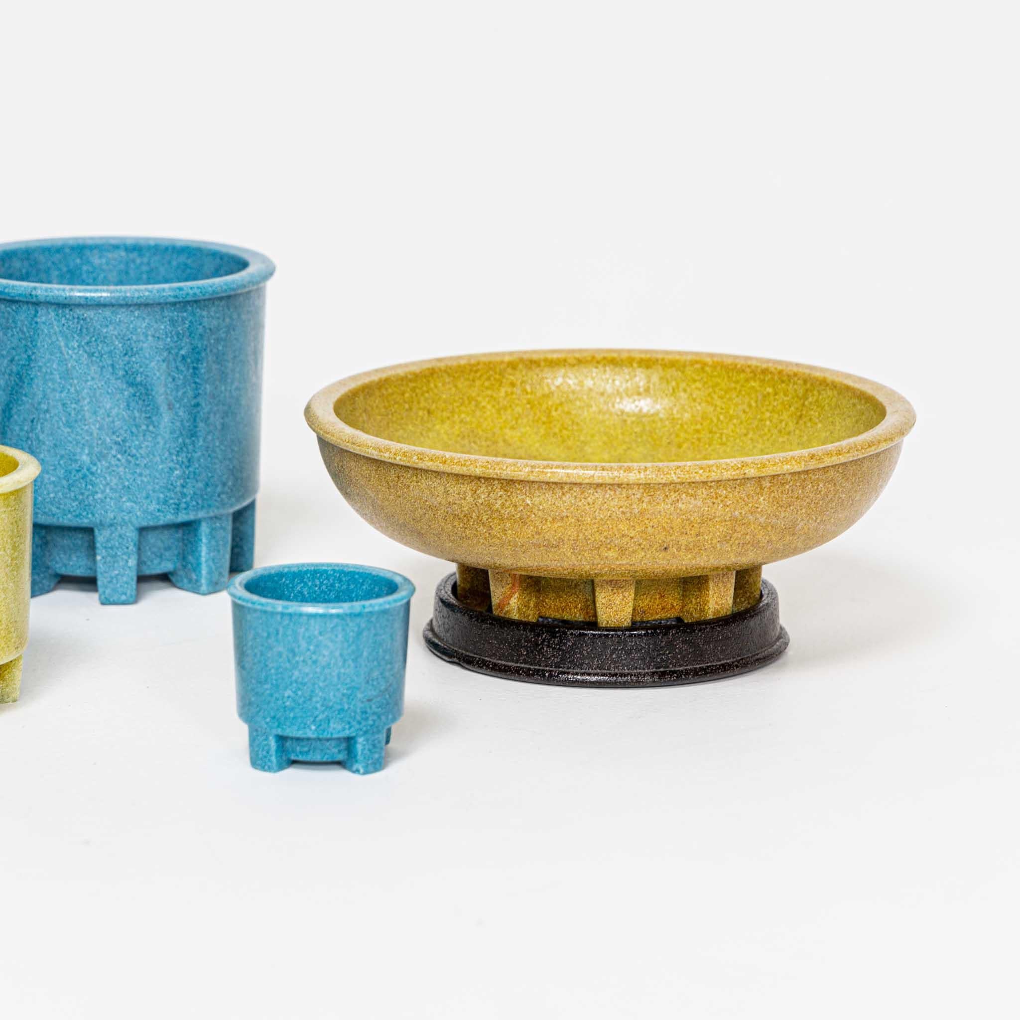Set of five flower pots in blue and yellow and two black coasters made of Graniver glass, specially designed for cacti. Dimensions: 12 x Ø13 cm, 9 x Ø22 cm, 7 x Ø18 cm, 8.5 x Ø9 cm, 6 x Ø6 cm.