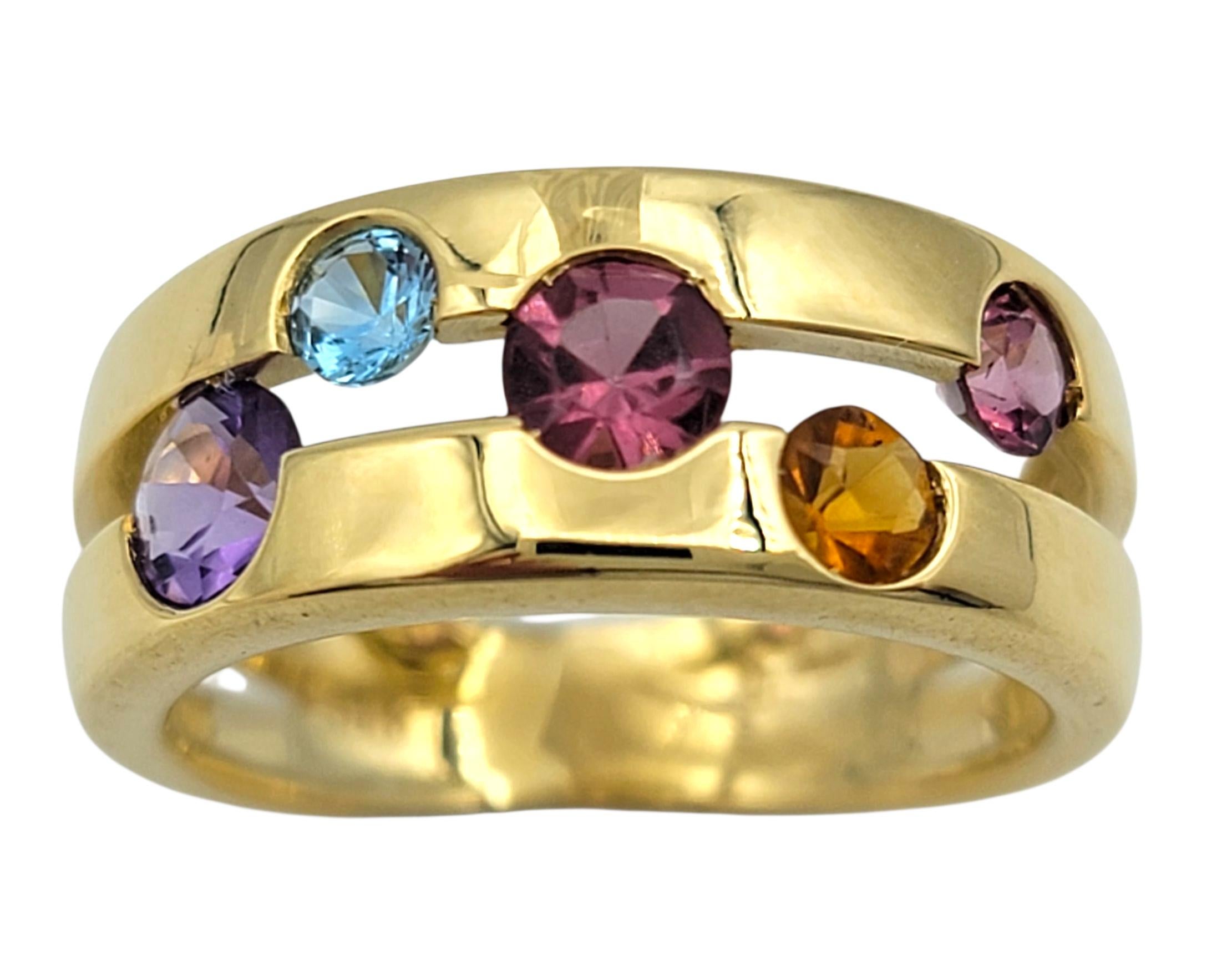 Taille de lla bague : 6

Cette bague vibrante est fabriquée en or jaune 18 carats et présente une silhouette audacieuse à tige fendue, à la fois contemporaine et raffinée. La surface polie est rehaussée d'un ensemble coloré de pierres précieuses