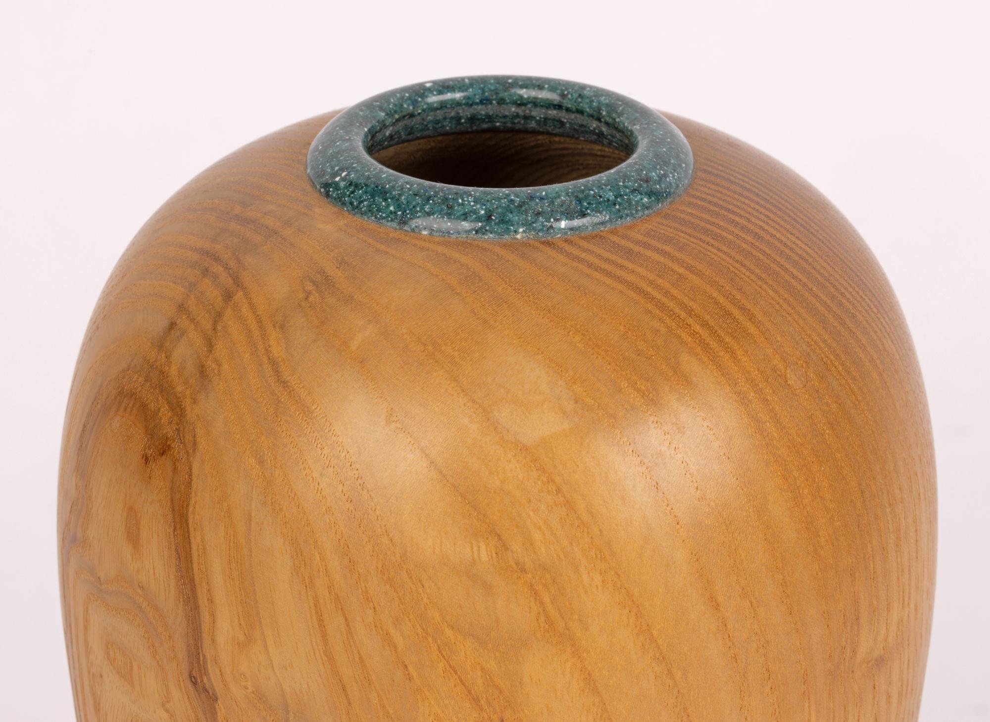 A finely hand-turned British hard wood ash vase with a green composite marble like rim dating by Andy James and dating from the 20th century. The vase of tall bulbous shape stands on a narrow flat round base and is turned from a single piece of wood