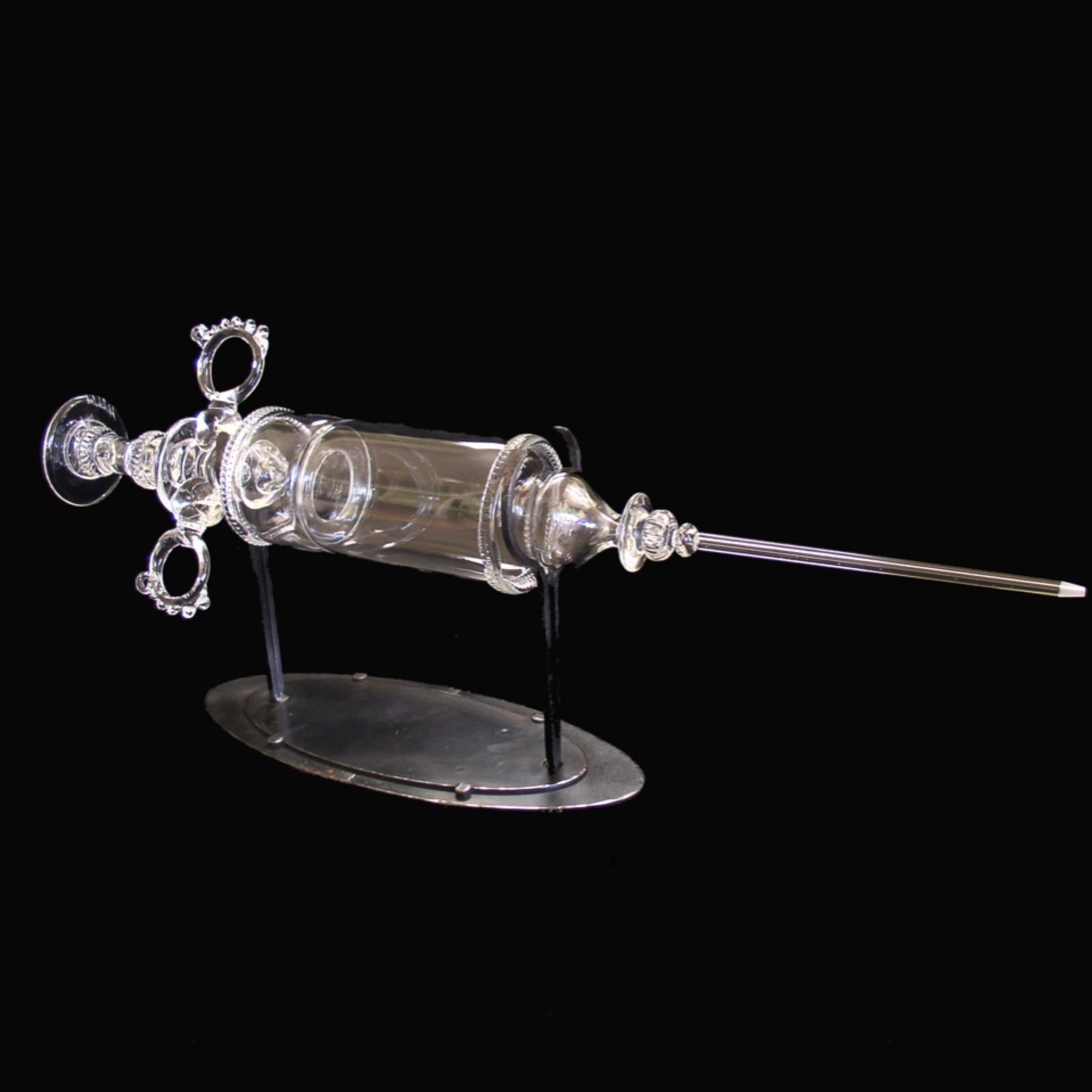 Large Blown Glass Syringe on Metal Stand

Hand Signed 2011 on Base

Can Be Turned On Base To Change Appearance

