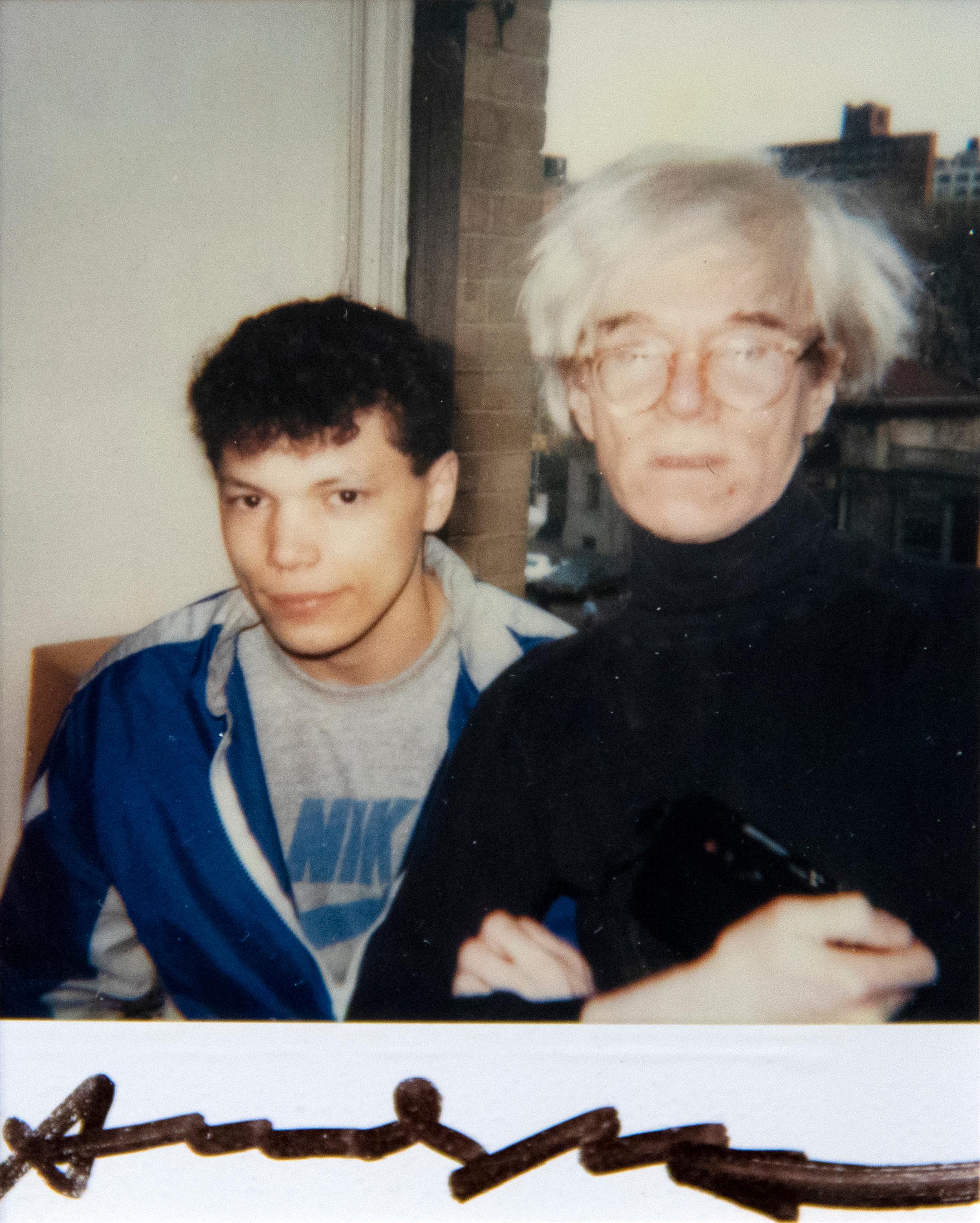 A photograph by Andy Warhol. "Andy Warhol and Unidentified Man" is a Polaroid, Polacolor by pop American artist Andy Warhol. The artwork is signed in the lower middle, "Andy Warhol", and is numbered FB01.00083 and AWL213.
Andy Warhol — who famously