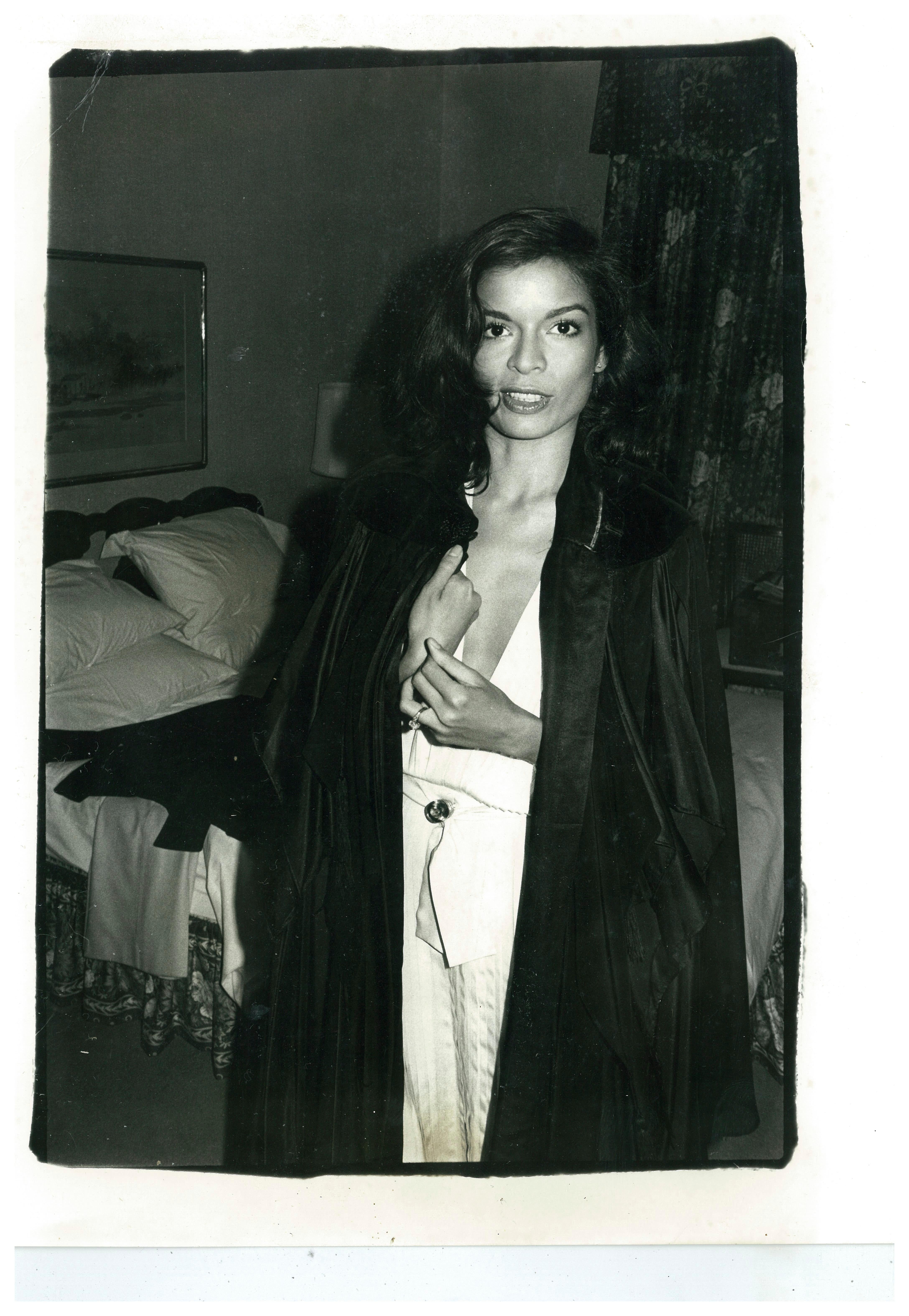 Bianca Jagger in black coat in Hotel Room