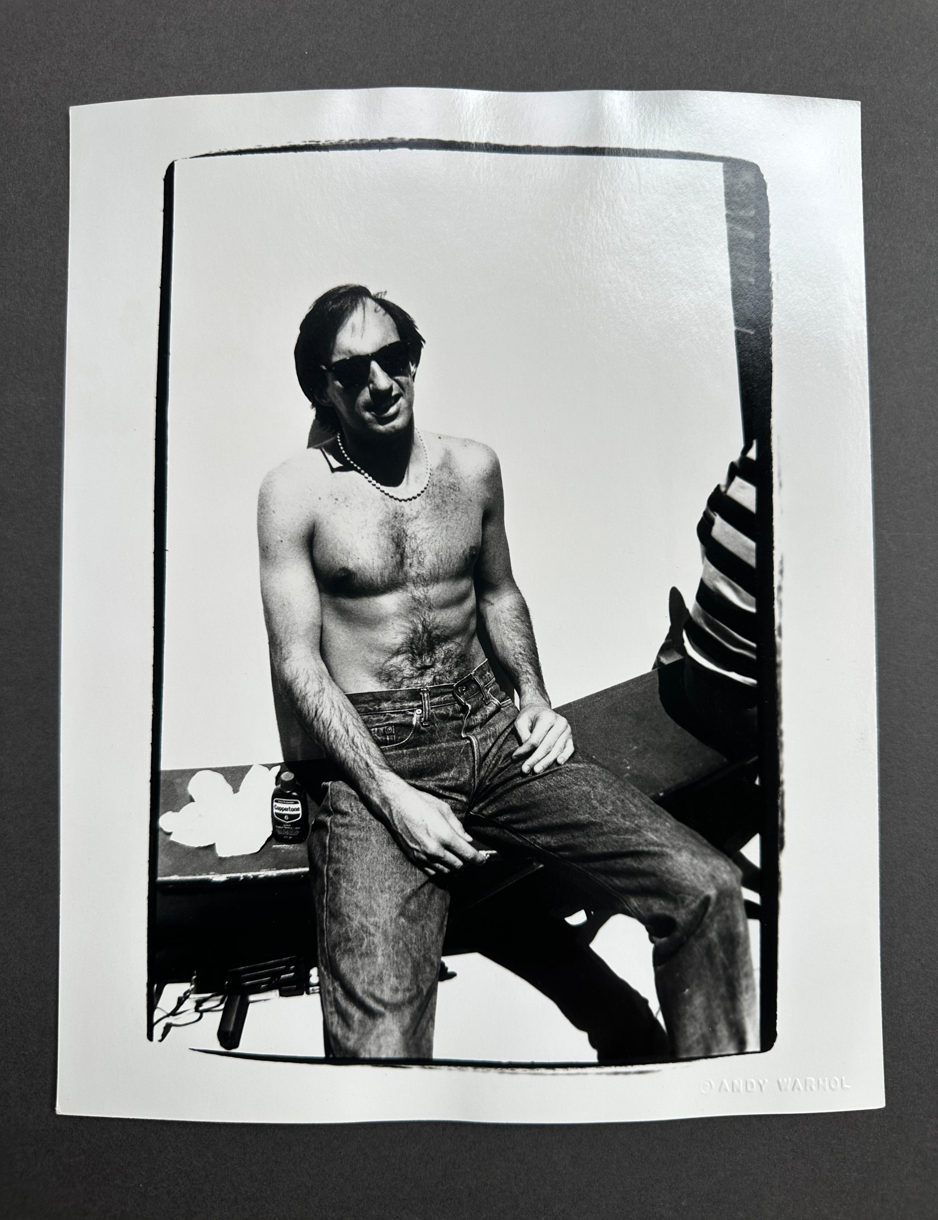 Jon Gould Sunbathing Shirtless with Jeans Seated in Cape Cod - Photograph by Andy Warhol
