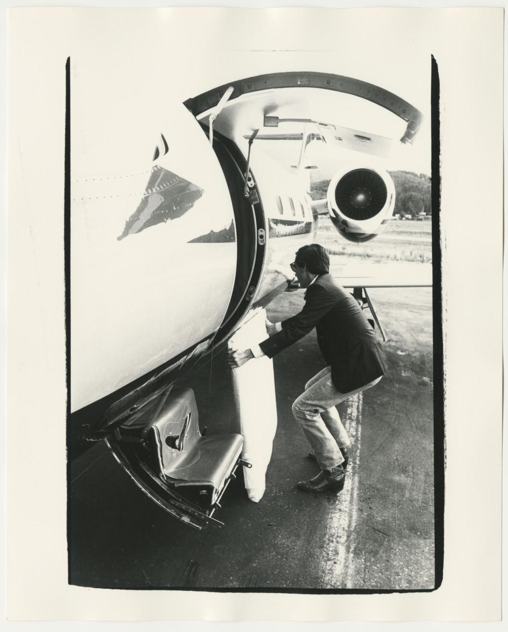 Black and White Photograph Andy Warhol - Fred Hughes chargeant une peinture de Warhol sur un jet Learjet 35