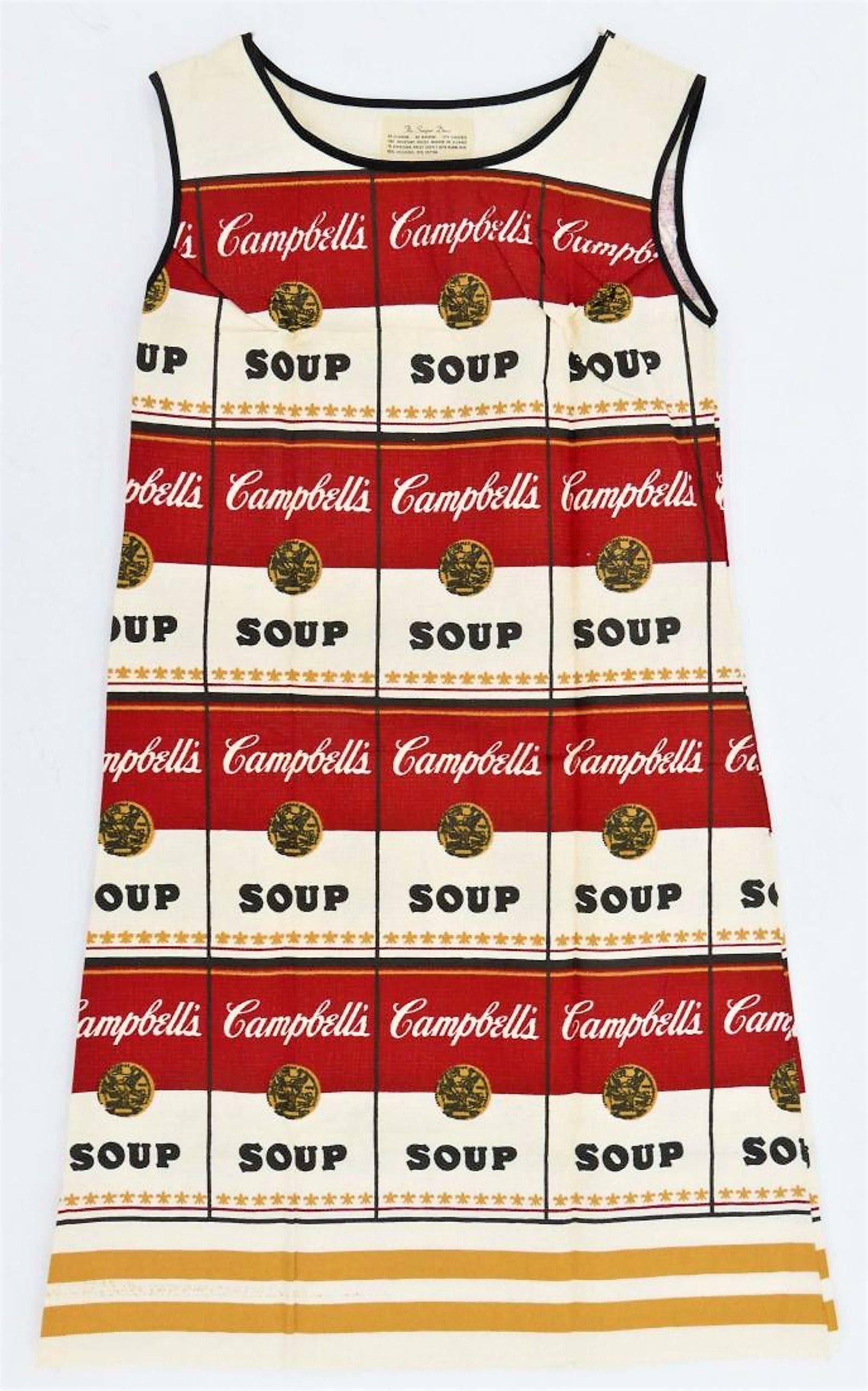 Créée en 1965, l'œuvre de Warhol, Souper Dress, évoque l'esprit de l'époque et notamment le mouvement Pop Art qui fusionnait l'art avec les matériaux de la vie urbaine contemporaine.  Le motif classique des boîtes de soupe rouges, noires et blanches