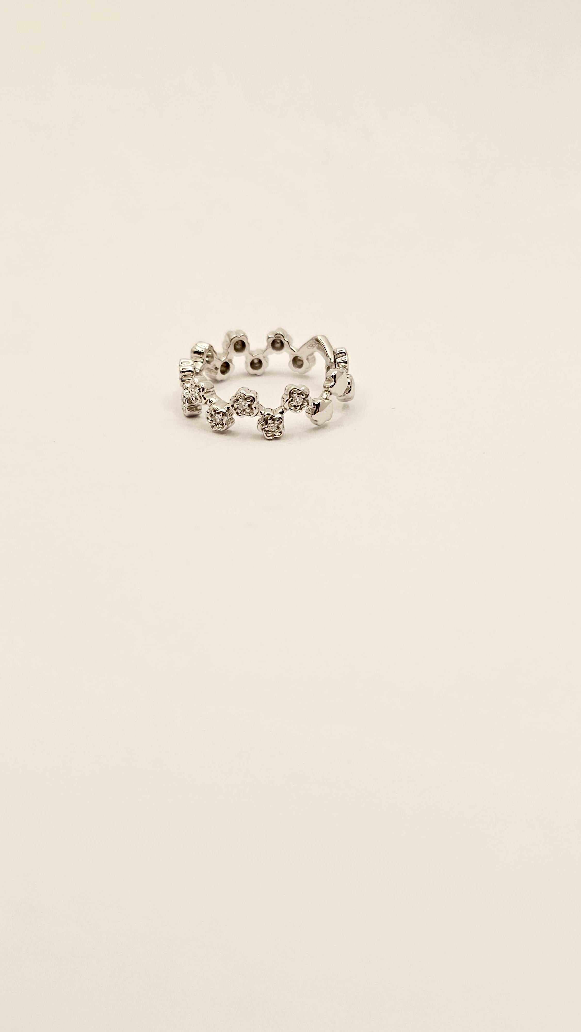 Una fedina a motivo floreale in oro bianco 18 Kt e Diamanti.
Questo anello è creato da piccoli fiori, ognuno di essi ha un Diamante al centro.
Nella parte dietro della fascia i fiori sono in oro, senza Diamanti, in modo da poter regolare la