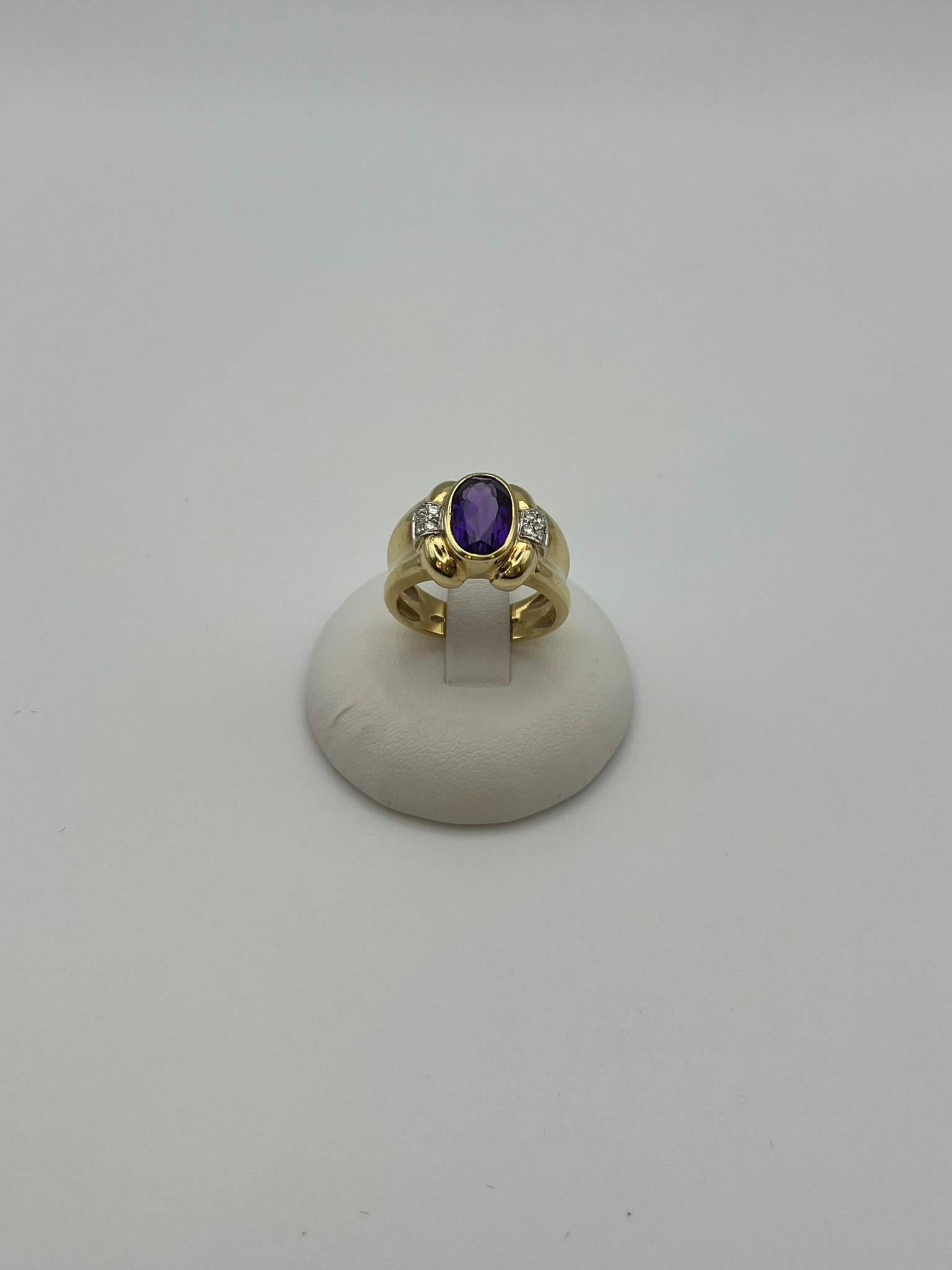 Elegante anillo artesanal de oro amarillo de 18 quilates, adornado con una espléndida amatista natural de talla ovalada y diamantes, talla brillante con un total de 0,16 quilates, engastados en los lados. Se trata de una joya única y atemporal que