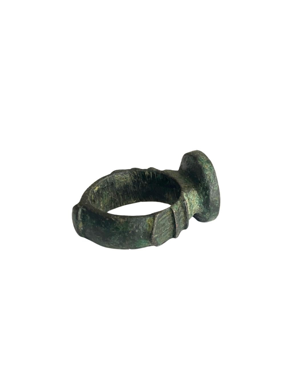 Large and ancient,
medieval bronze ring with notched shank and engraved bezel with pseudo-heraldic decoration.