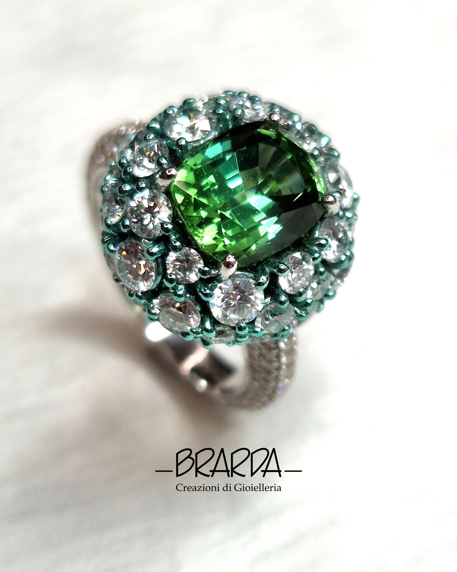 Quasto anello da cocktail fa parte della collezione GLOBO, dove una semisfera di diamanti bianchi taglio brillante, in un mix di misure, sorregge una pietra centrale che in questo caso è una bellissiama Tormalina verde taglio cuscino dal peso di