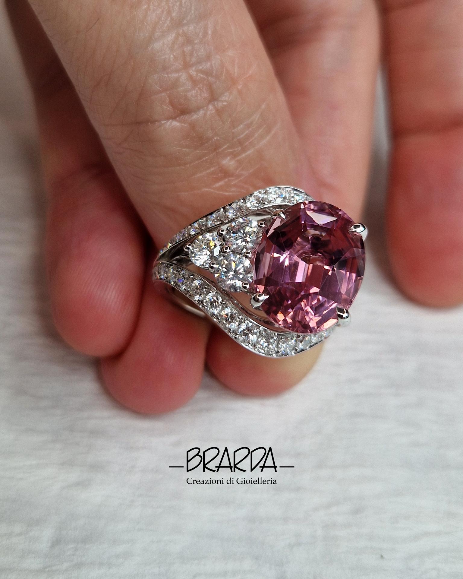 This cocktail ring has an asymmetric geometry that contrasts a beautiful pink Tourmaline on one side, with a vibrant and bright tone, oval cut ct 7.38 (from Nigeria) on the other side diamonds. The double shank structure is also completely set with