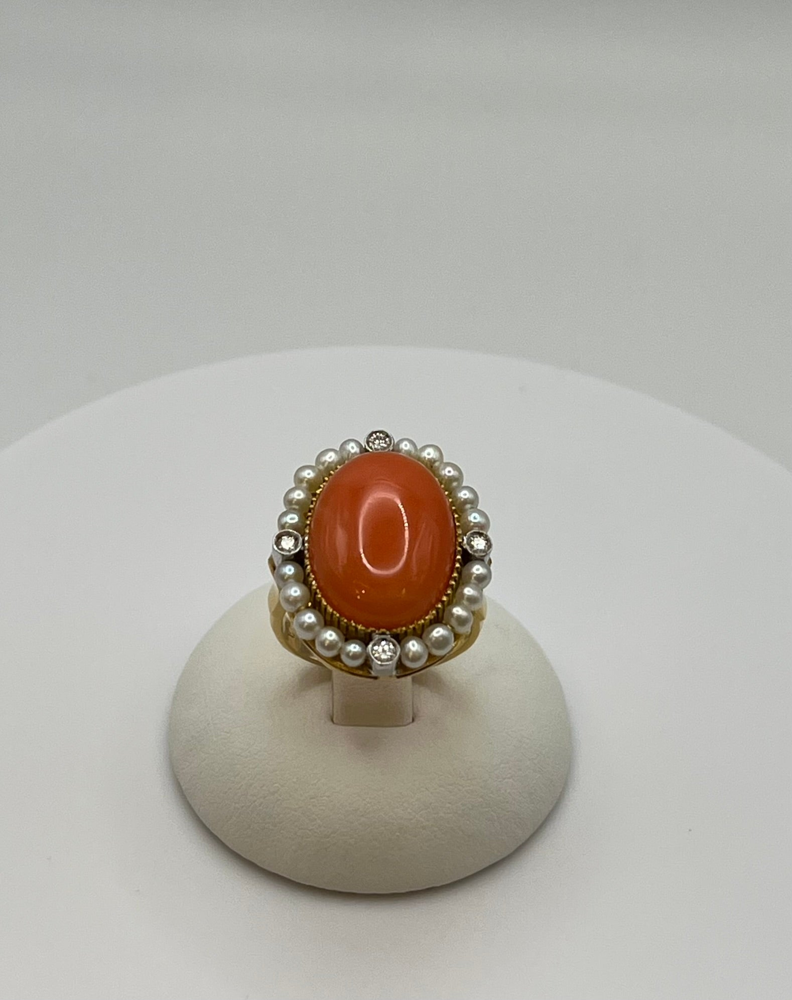 Questo anello prodotto artigianalmente in Italia negli anni '90 è un mix perfetto tra eleganza e classicità, è interamente in oro giallo 18 kt. e presenta al centro un meraviglioso corallo giapponese, adornato da perle akoya e diamanti tagliati a