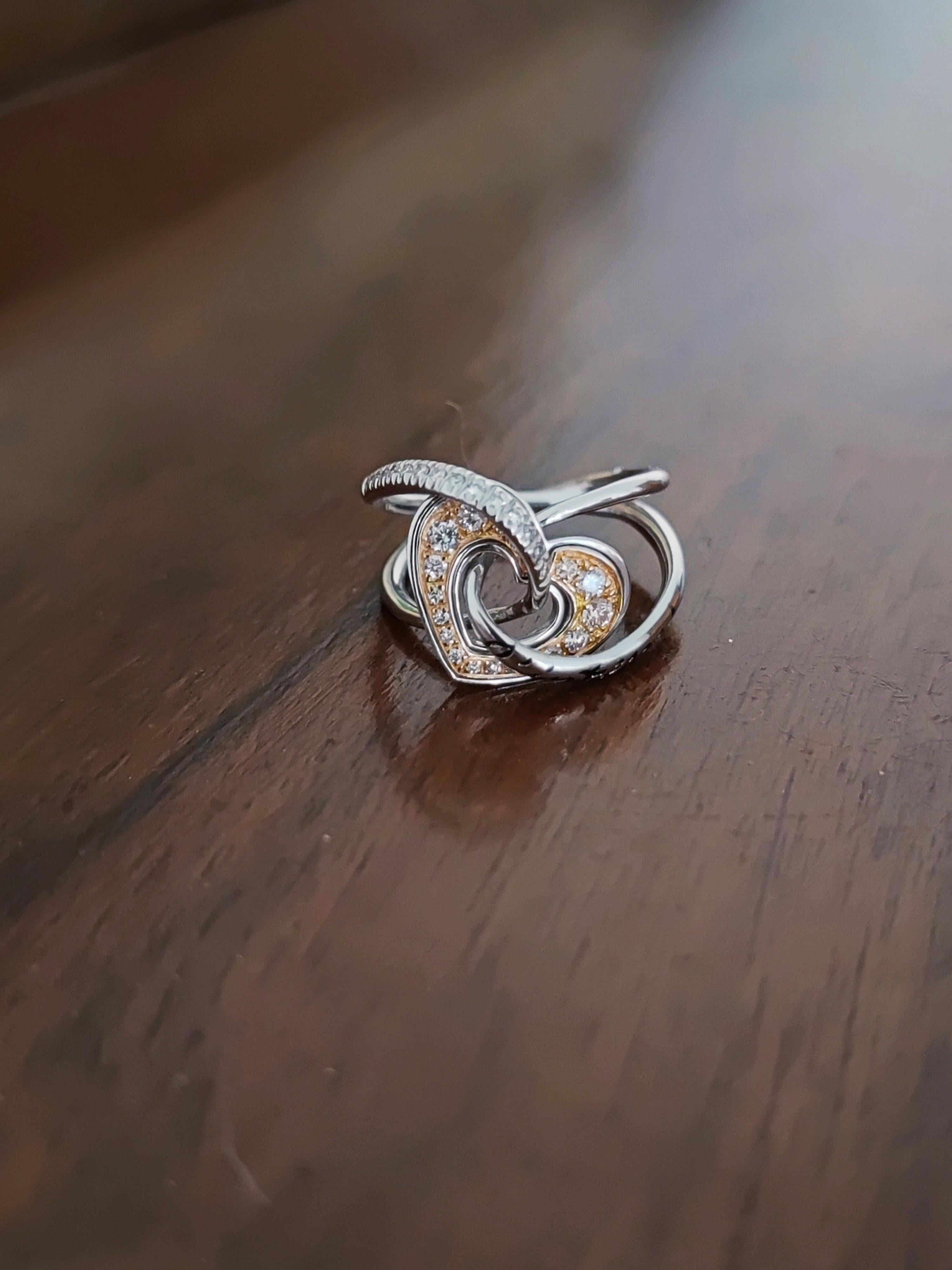 A 750‰ white gold ring with a sculptural and refined design, featuring a fluid interweaving of forms that wind in a harmonious and continuous movement. The two main lines, shaped with balance and skill, meet in an elegant knot that becomes the heart