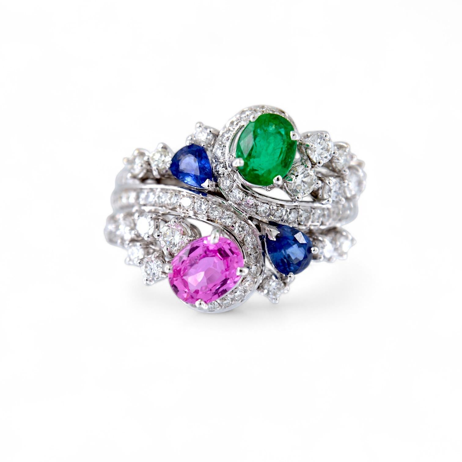 Laissez-vous séduire par le raffinement de cette bague en or blanc 18 carats fabriquée à la main. Au centre, une splendide émeraude de 0,89 carat est rejointe par un élégant saphir rose de 1,22 carat, accompagné de deux gouttes de saphir bleu d'un