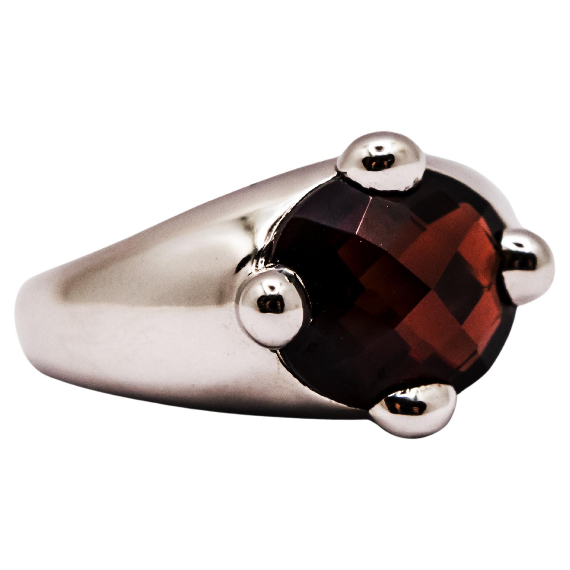 A 1990s design ring in solid 18 kt white gold weighing 9.30 g.
Embellished with a beautiful garnet that is dark red and transparent at the same time and has an oval faceted cut.
The unusual cut of the stone, the contrasting red and white colors, and