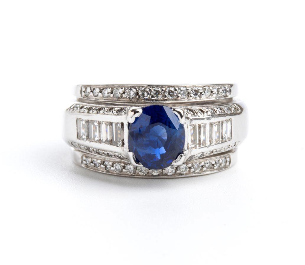 Mit Diamanten und einem Saphir besetzter Goldring mit einem zentralen Saphir, der mit Diamanten in verschiedenen Formen besetzt ist.
Nr. 01 ovaler Saphir, Verbundschliff, 1,52 ct. Fehlen von Angaben zur Wärmebehandlung. 
Nr. 58 Diamanten, rechteckig
