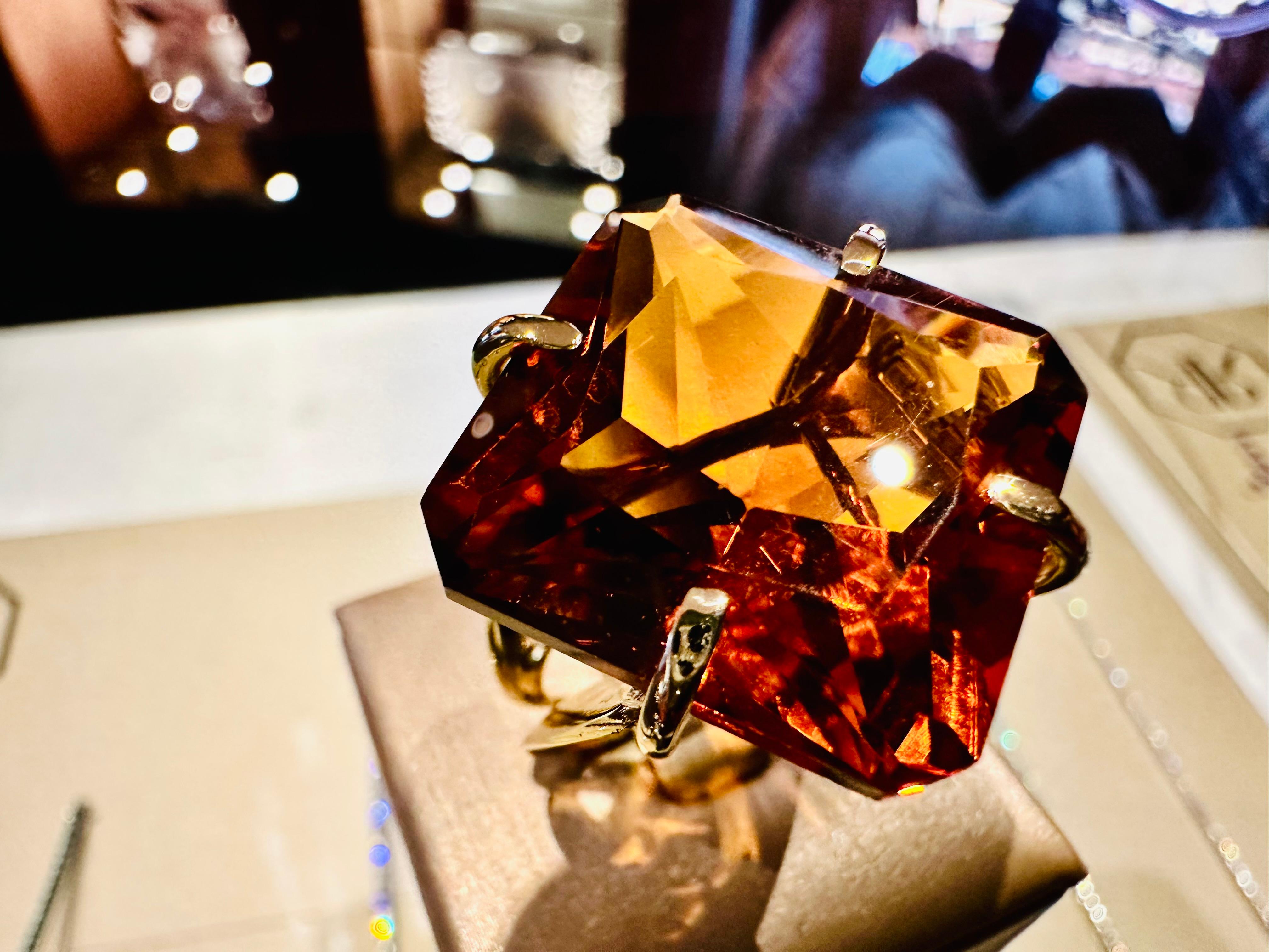 Icône du luxe et de l'artisanat, cette bague est une création extraordinaire en or jaune 18 carats, conçue pour rehausser la magnificence d'une imposante topaze citrine de taille princesse. La pierre de taille généreuse (2 cm x 2 cm) se distingue