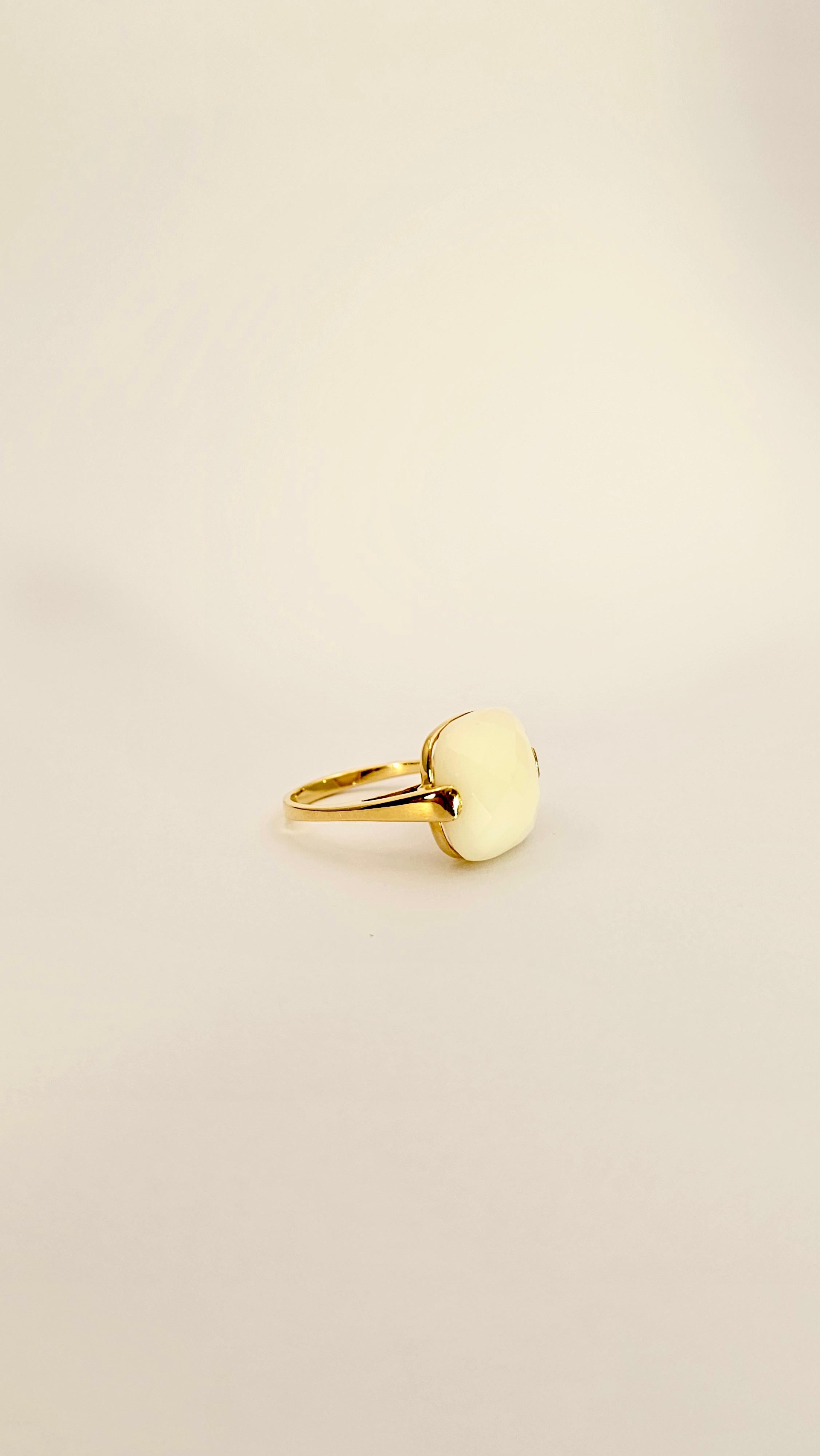 A ring with a sleek design and elegant geometric shapes.
Handcrafted in 18 kt yellow gold and embellished with a faceted, square-cut white Agate.
The stone measures 18 x 18 mm, is convex at the top and flat at the bottom.
The faceted cut of the