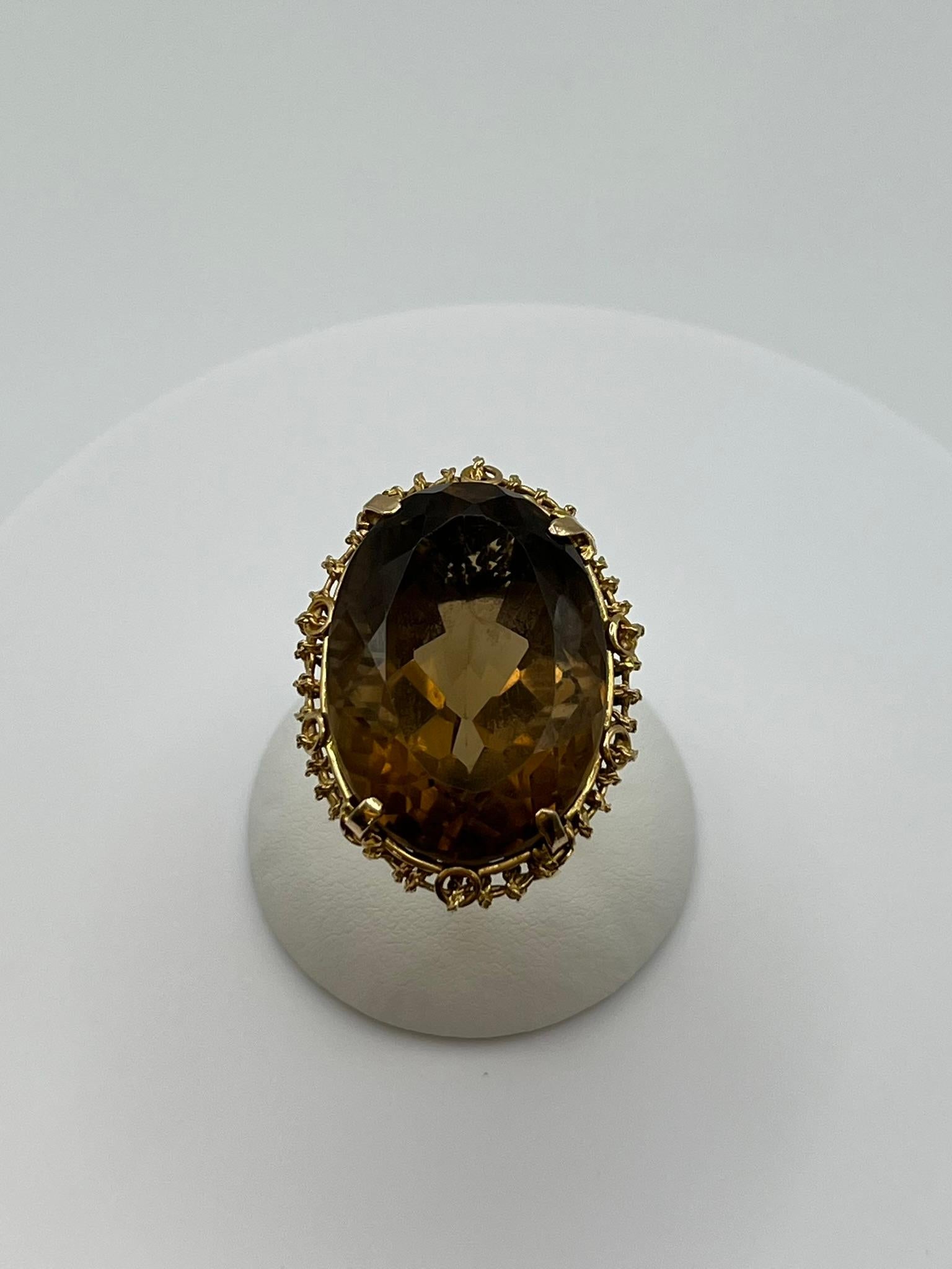Cette bague a été créée pour illuminer la main de la personne qui la porte. Sa caractéristique principale est un quartz citrine fumé central serti dans un panier en or jaune 18 carats fait à la main avec des fils torsadés, qui est à la fois robuste