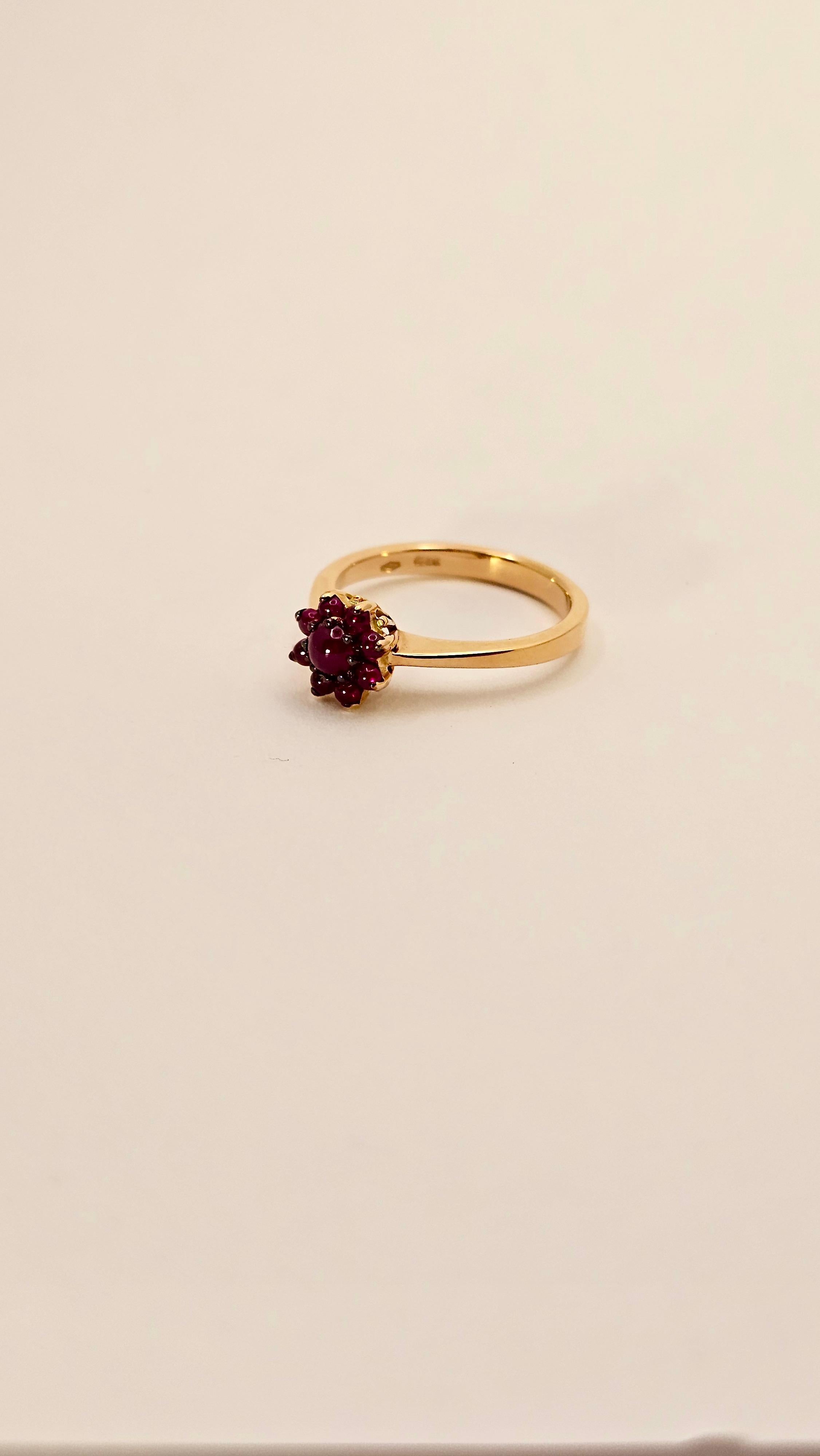 Un delizioso anello in oro rosa 18 Kt e Rubini taglio Cabochon del peso di 0.78 carati.
Questo anello è realizzato interamente a mano. Ha un caratteristico design in stile anni '60. 
Il motivo a fiore è composto da 9 Rubini di colore rosso intenso,