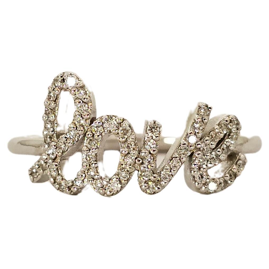 A ring with a contemporary and romantic design.
Made of solid 18 kt white gold weighing 2.30 grams.
The 750 gold hallmark is shown on the inside of the band.

The LOVE inscription, in a modern cursive font, is embellished with natural white Diamonds