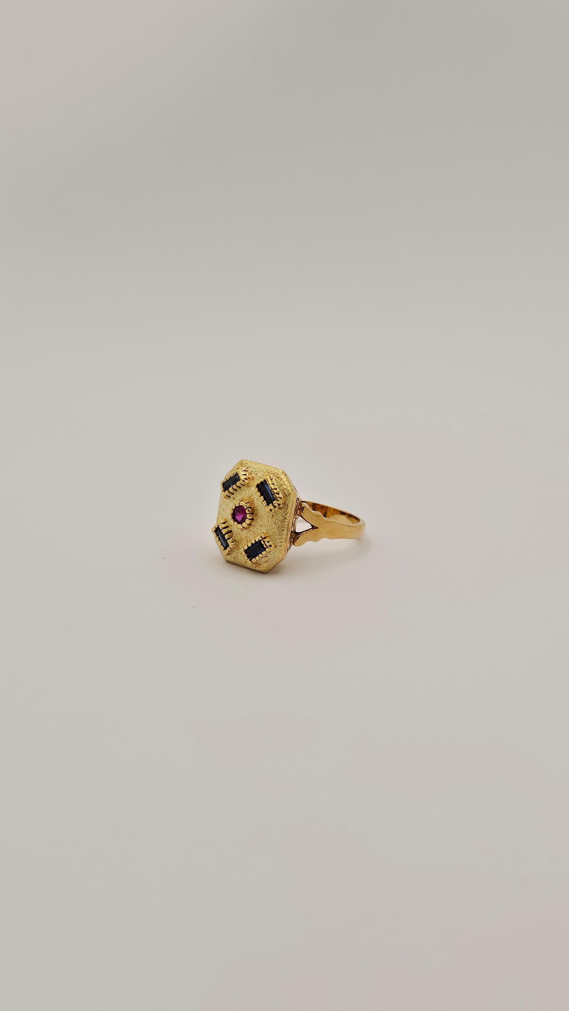 Bague vintage de style moderniste datant des années 1970, en or massif 18 carats.
Cette bague se compose d'une partie supérieure octogonale sur laquelle sont sertis quatre saphirs bleu foncé taillés en hexagone et un rubis rond taillé en